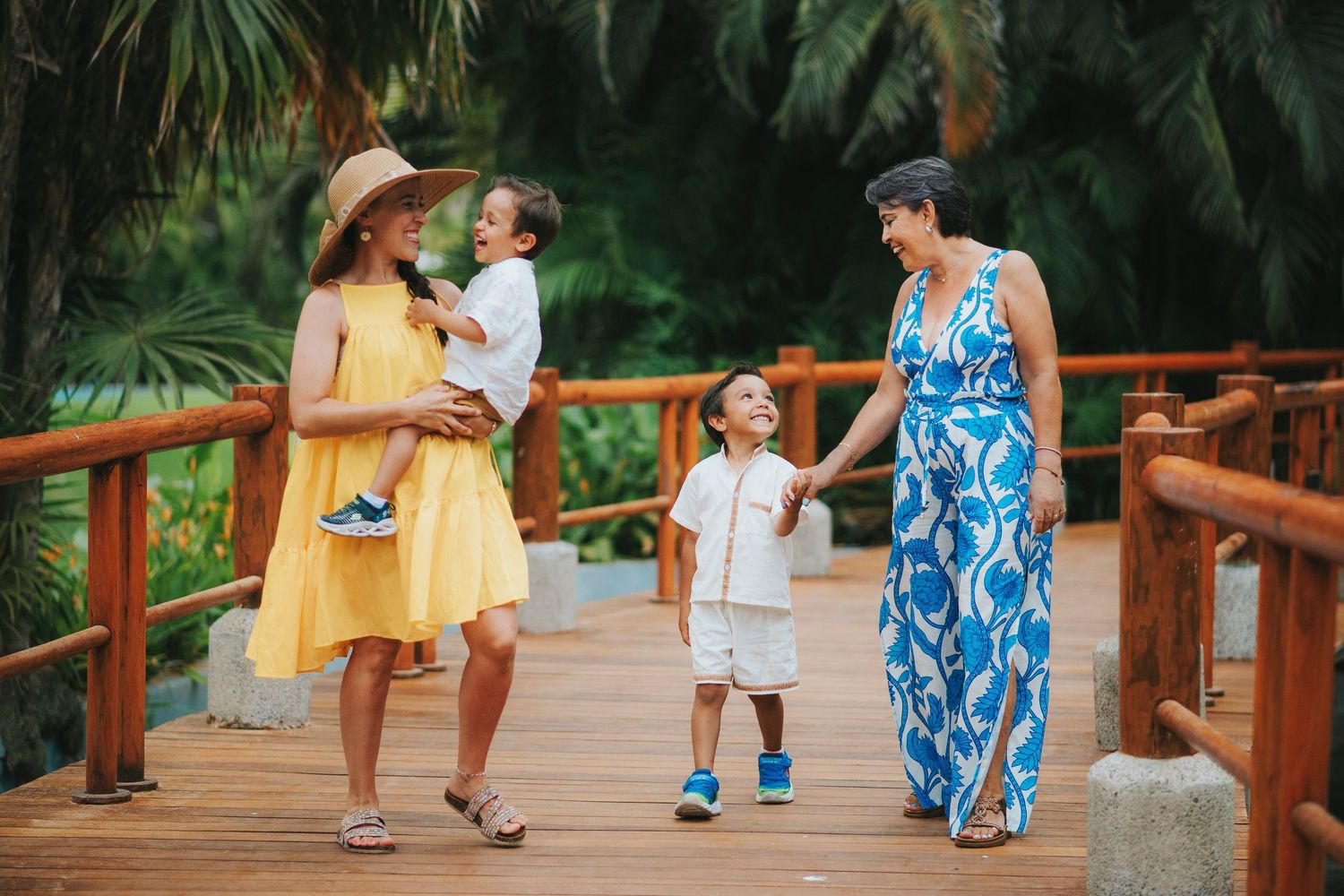 Family walking along a wooden boardwalk surrounded by tropical plants.