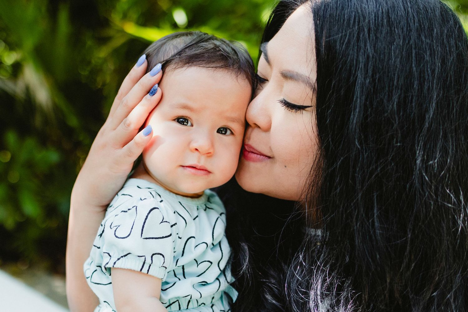 Mother giving gentle kiss to baby during intimate lifestyle photo session.