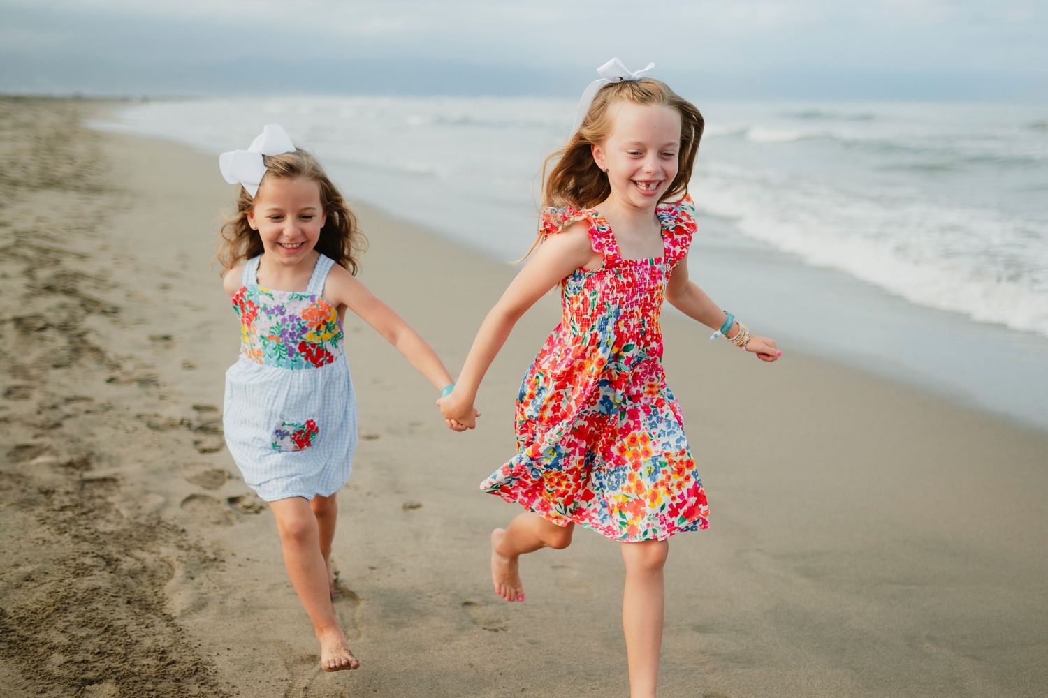 Children playing and running joyfully on a sandy beach at sunset.
