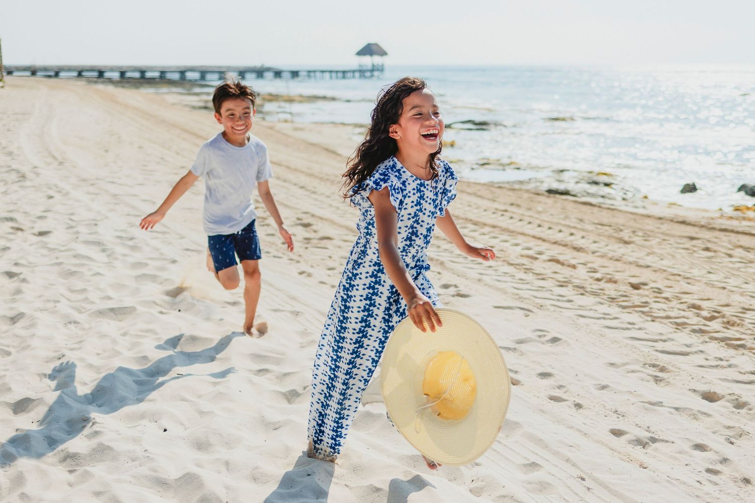 Family plays joyfully together on a sunny beach with yellow ball.