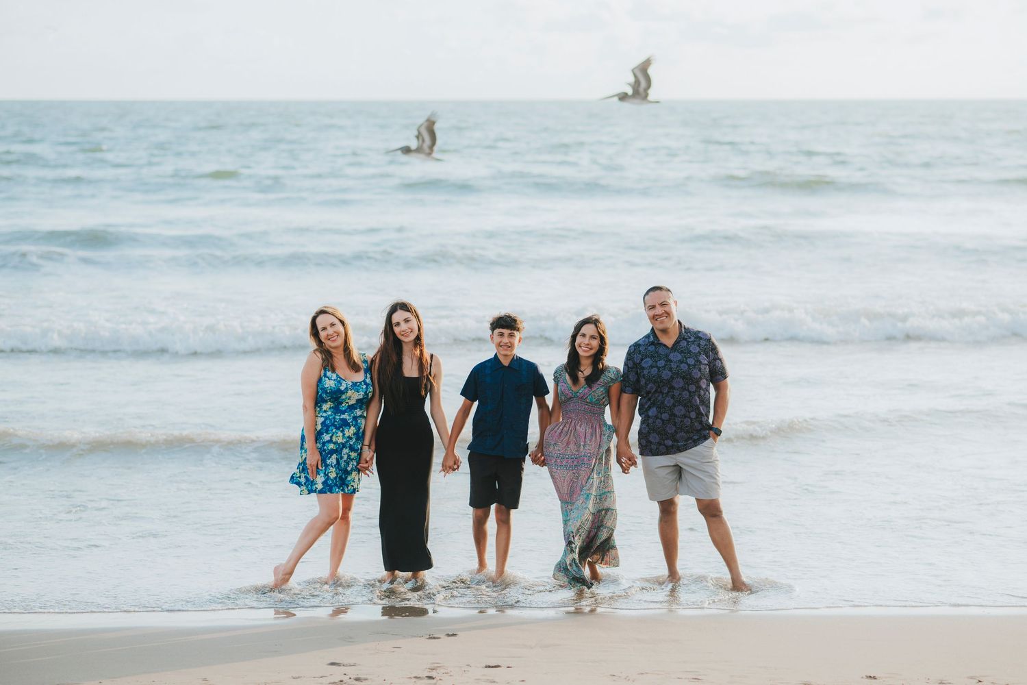 Family walking together along a scenic beach shoreline during sunset.