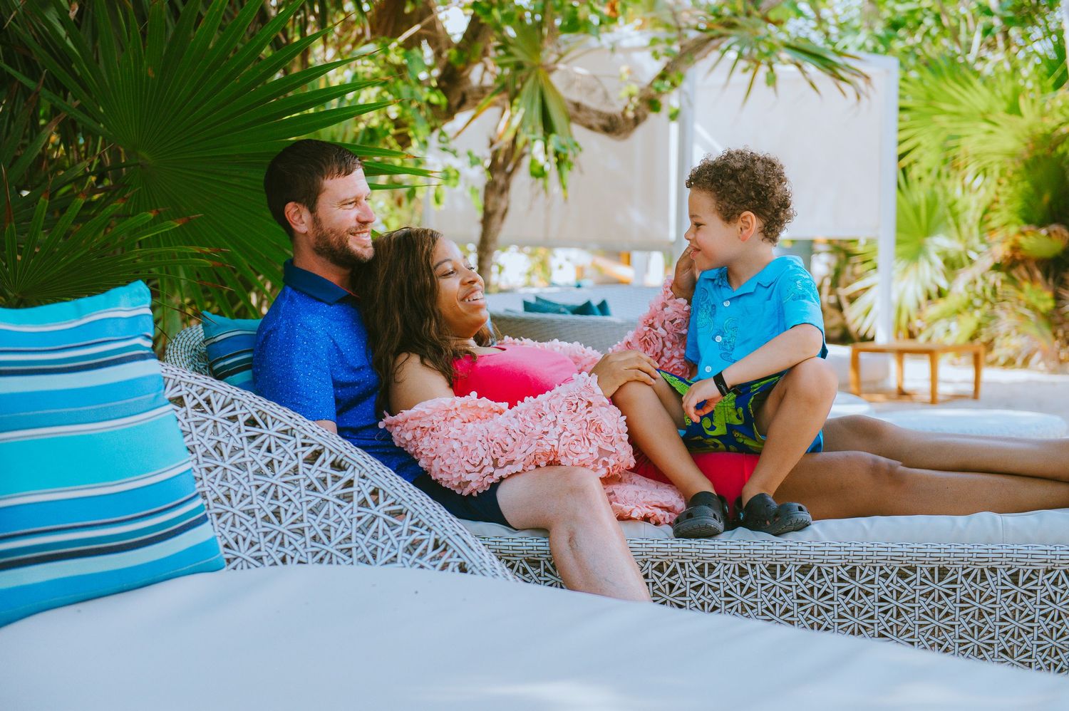 Couple relaxing on a white outdoor daybed surrounded by tropical greenery.
