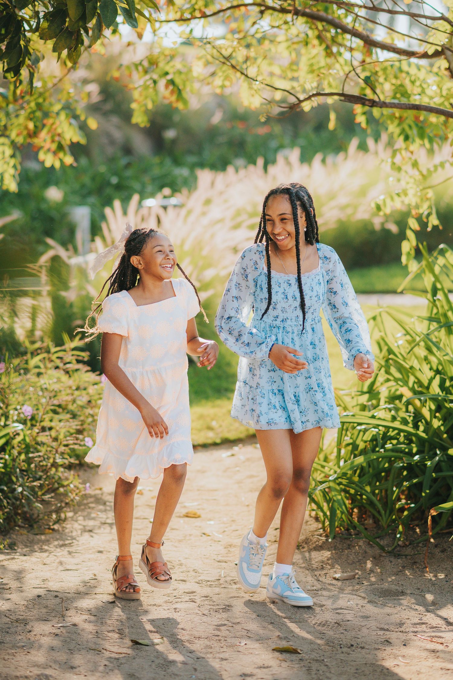 Two children playing together outdoors in matching blue and white summer outfits.