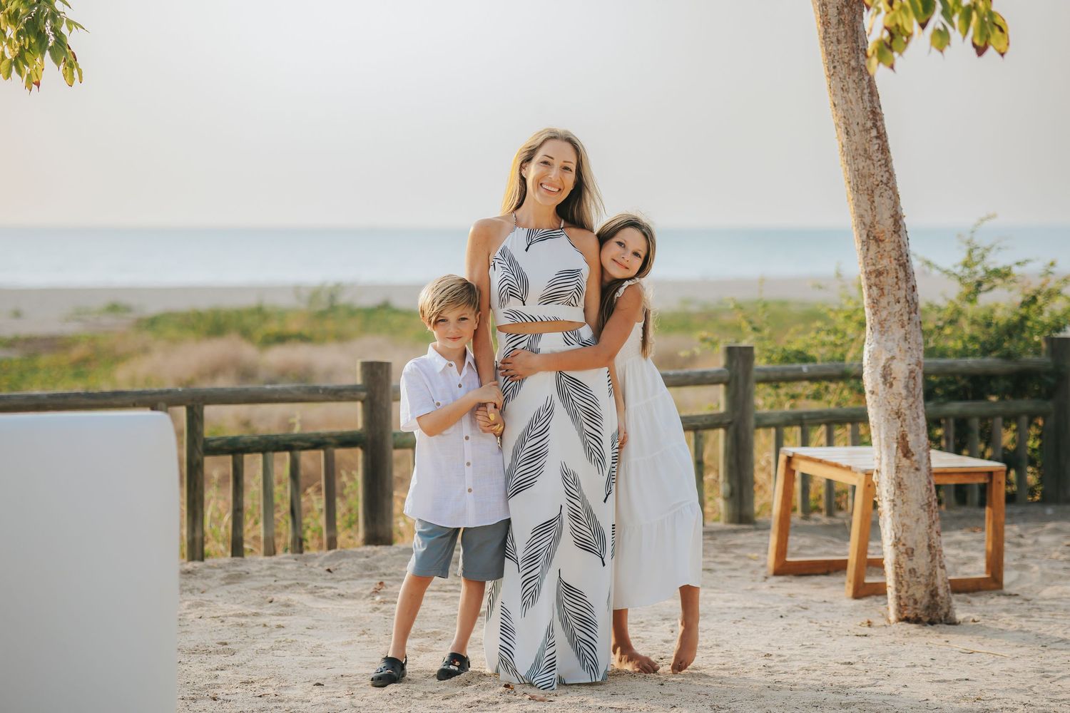 Family enjoying a sunny day together on a wooden boardwalk near the beach.