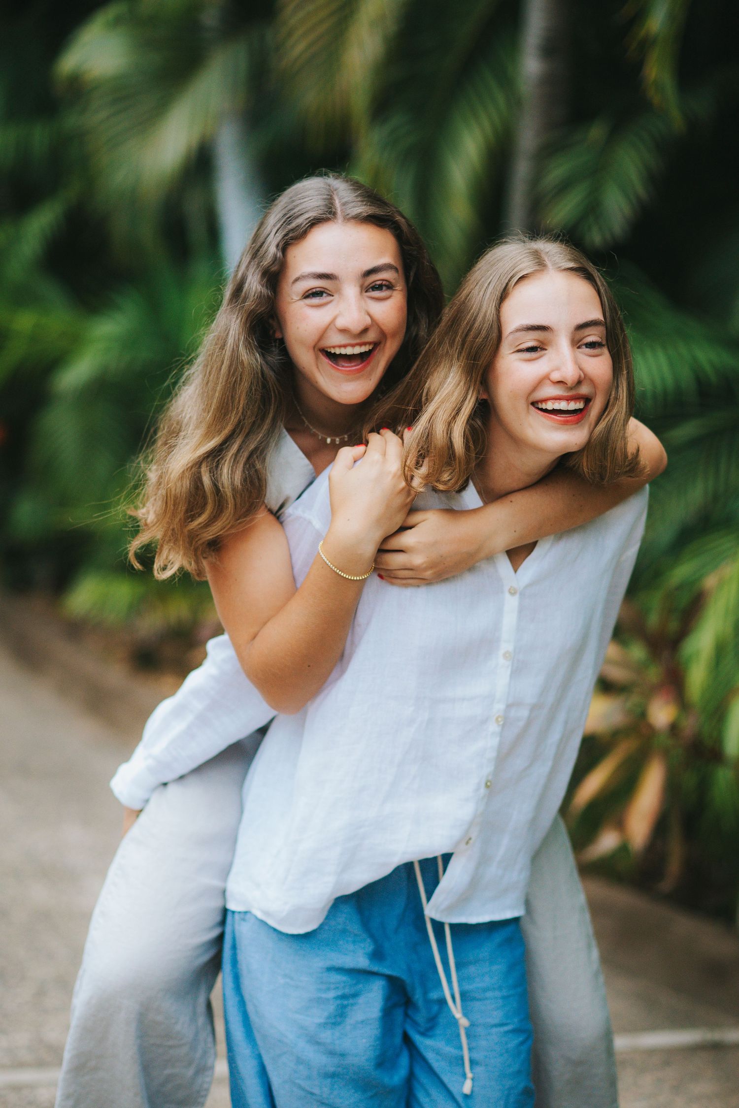 Friends sharing laughter and embraces against a tropical palm background.