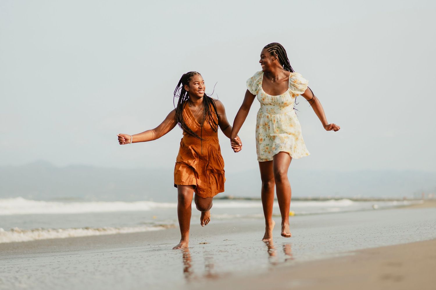 People running and playing together on a sandy beach at sunset.