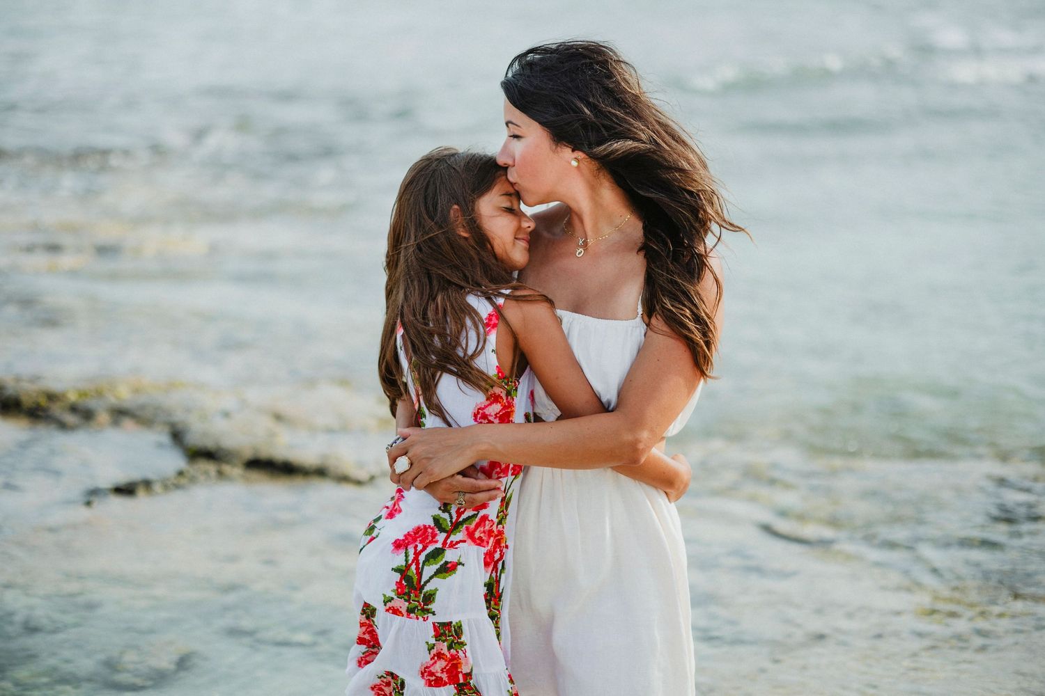 Beachside portrait session with floral dresses against ocean backdrop.