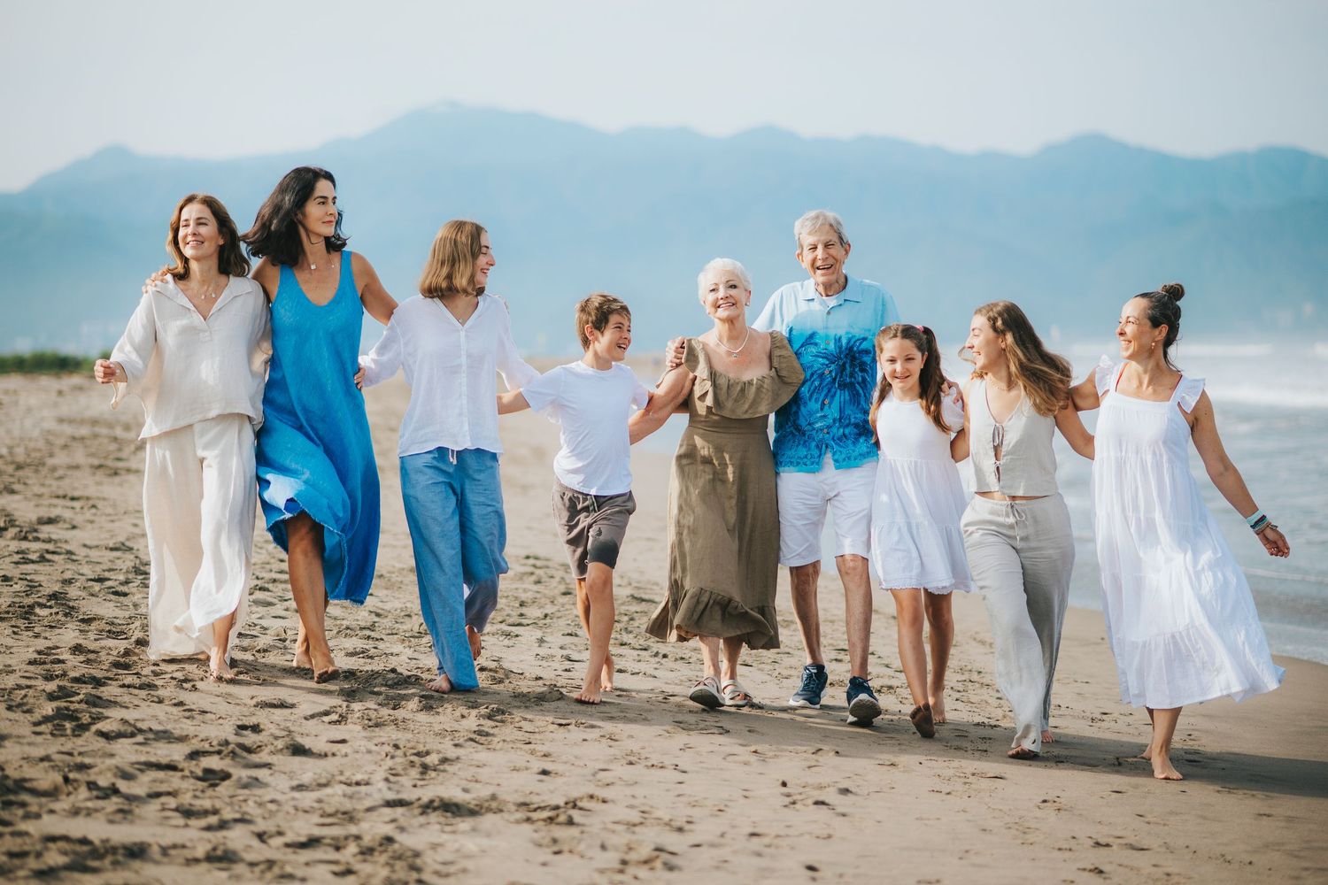 A group walking together along the beach in coordinated blue and white outfits.