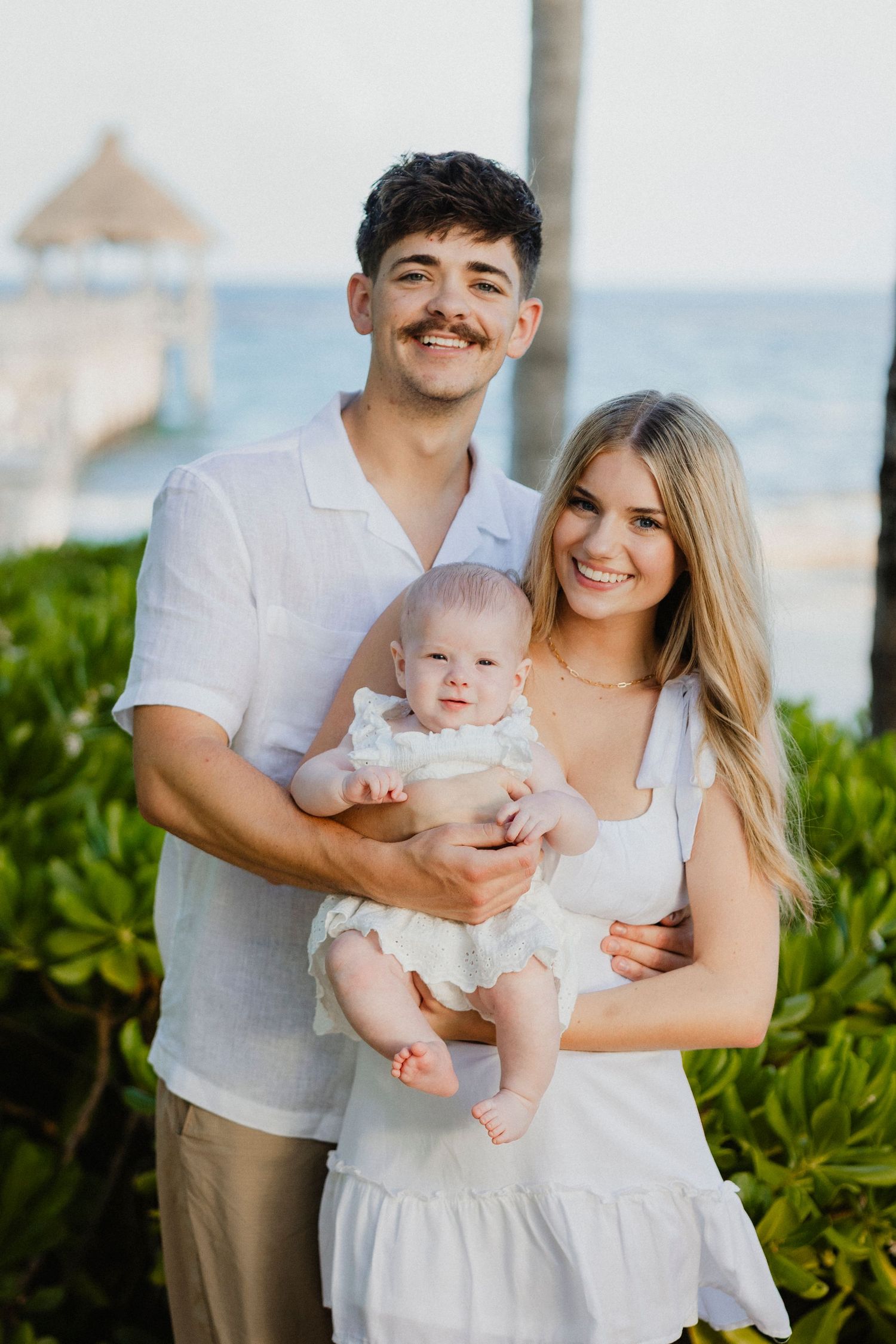 Family portrait session at a beachfront location with palm trees and ocean views.