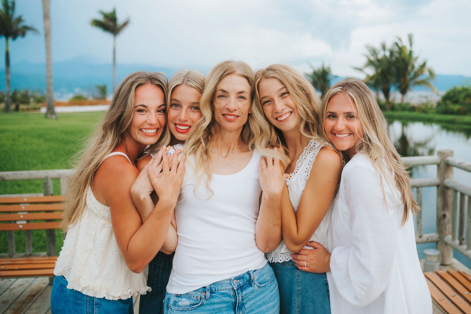 Friends in coordinated white and blue outfits posing together in a tropical location.