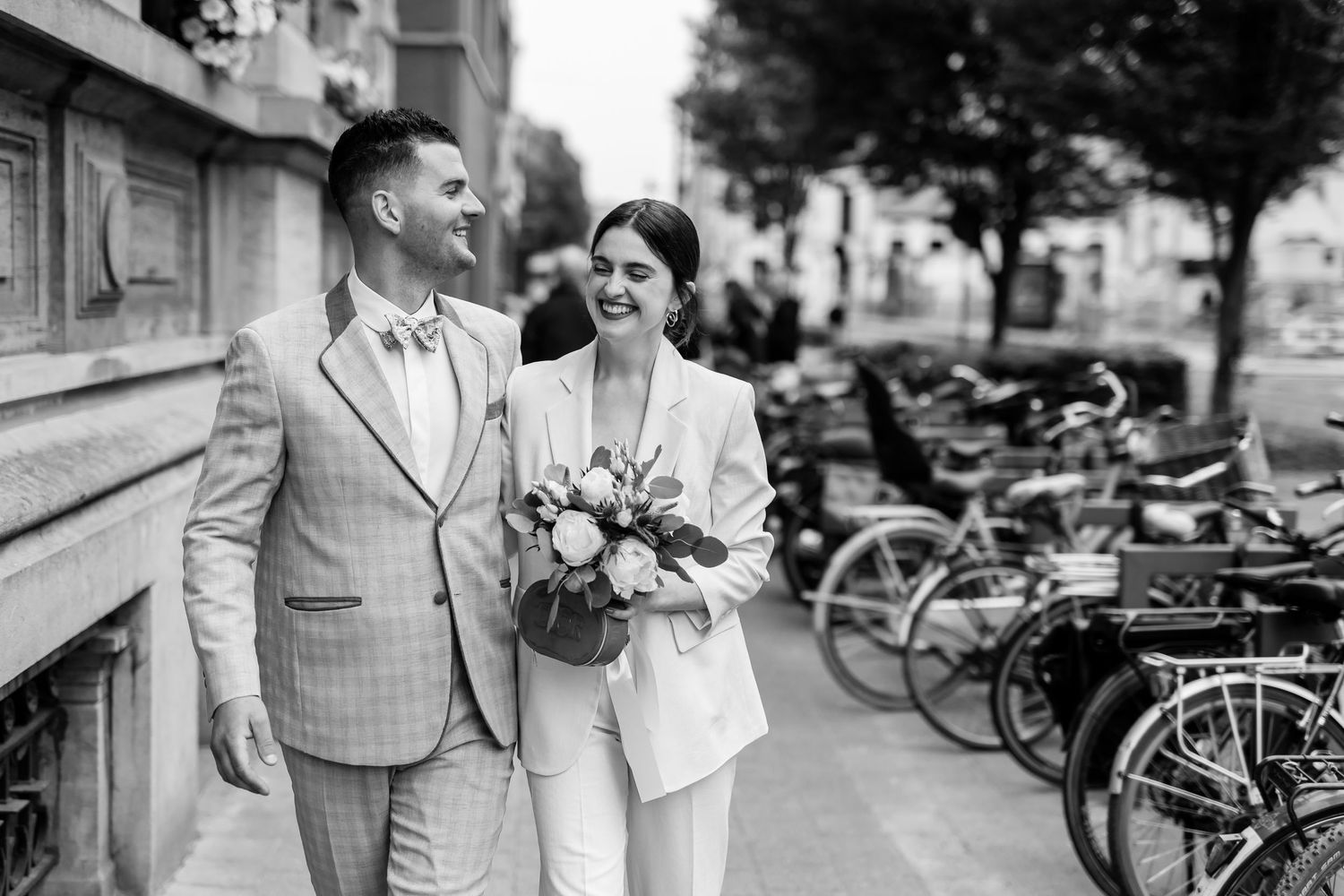 A couple in vintage 1950s style clothing walk together on a city street with bicycles in the background.