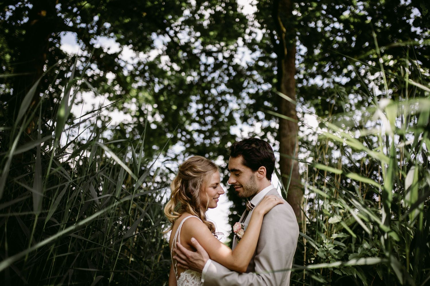 A romantic couple embraces in a lush garden setting during a wedding photo session.