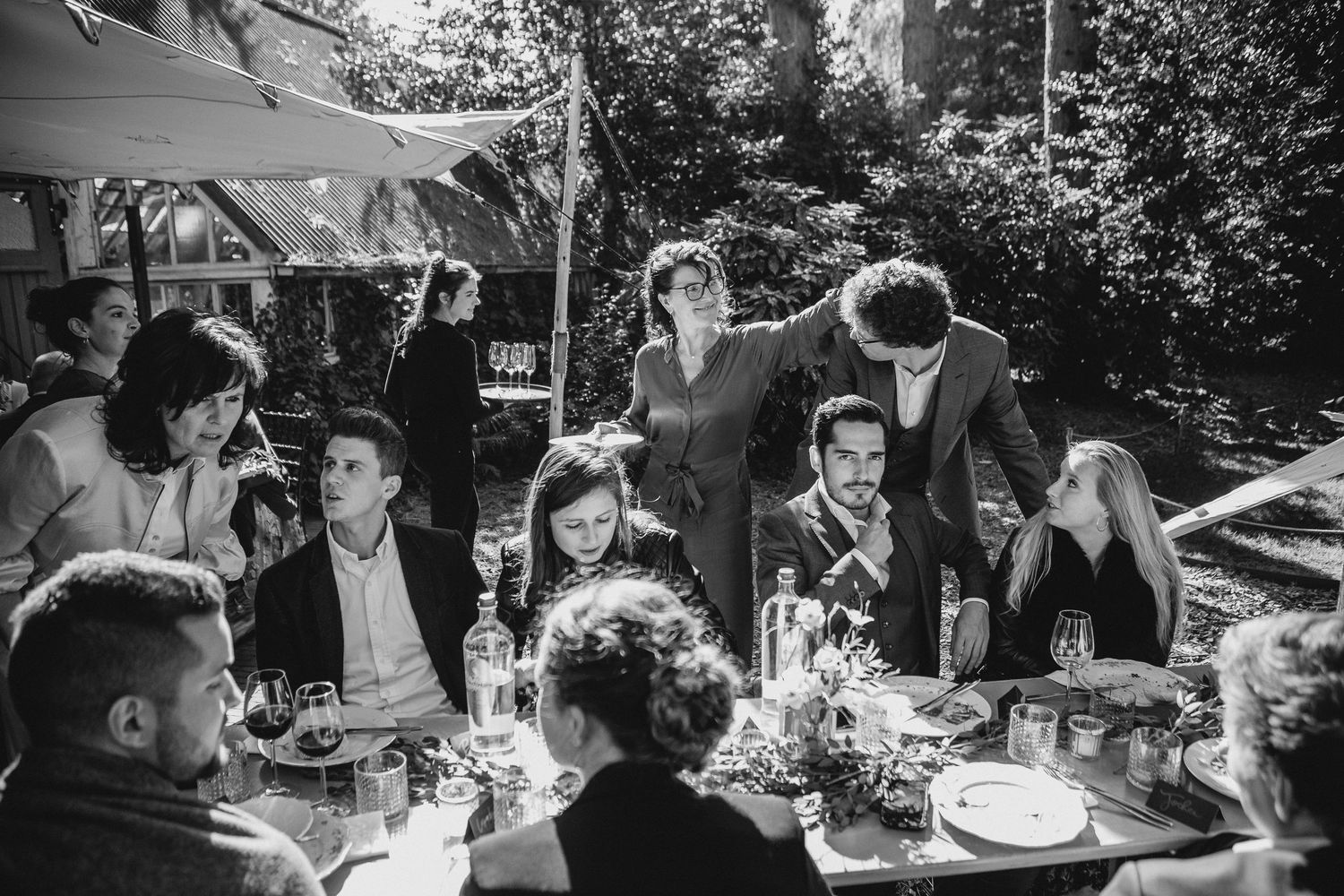 A collection of black and white photos showing people gathered at outdoor tables for a celebratory meal or event.