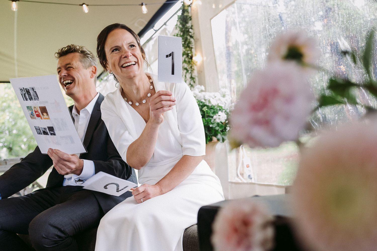 A joyful wedding celebration moment captured as people laugh together during an outdoor reception.