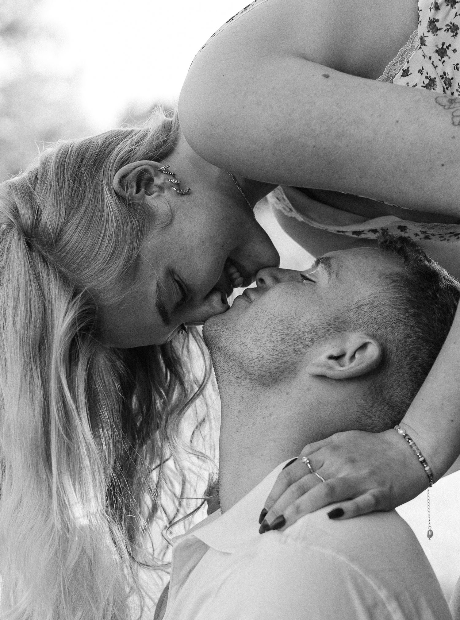 Black and white photo of a romantic couple sharing a tender kiss outdoors.