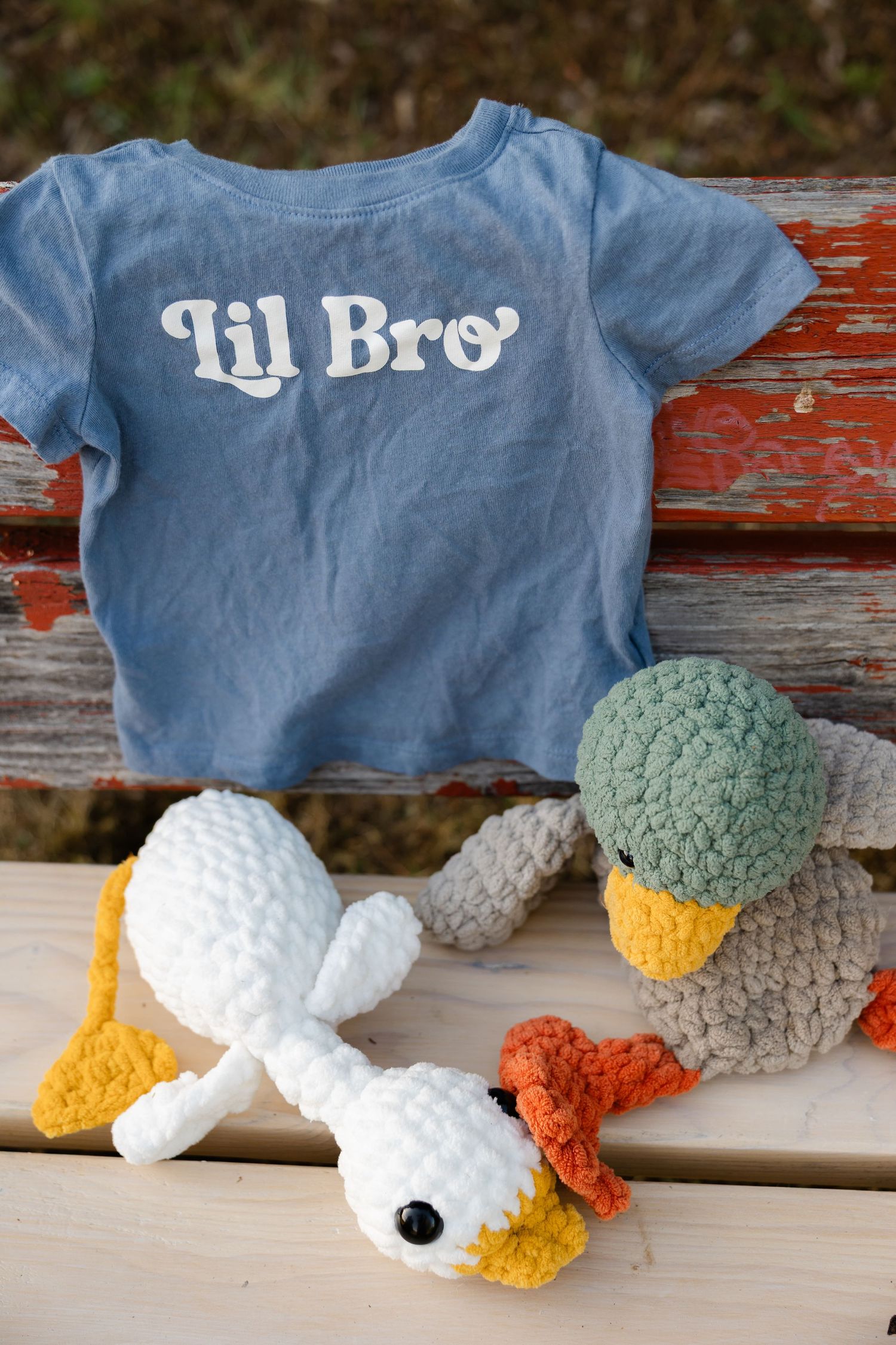 Blue Lil Bro toddler t-shirt on bench with two crocheted duck stuffed animals, perfect sibling announcement gift.