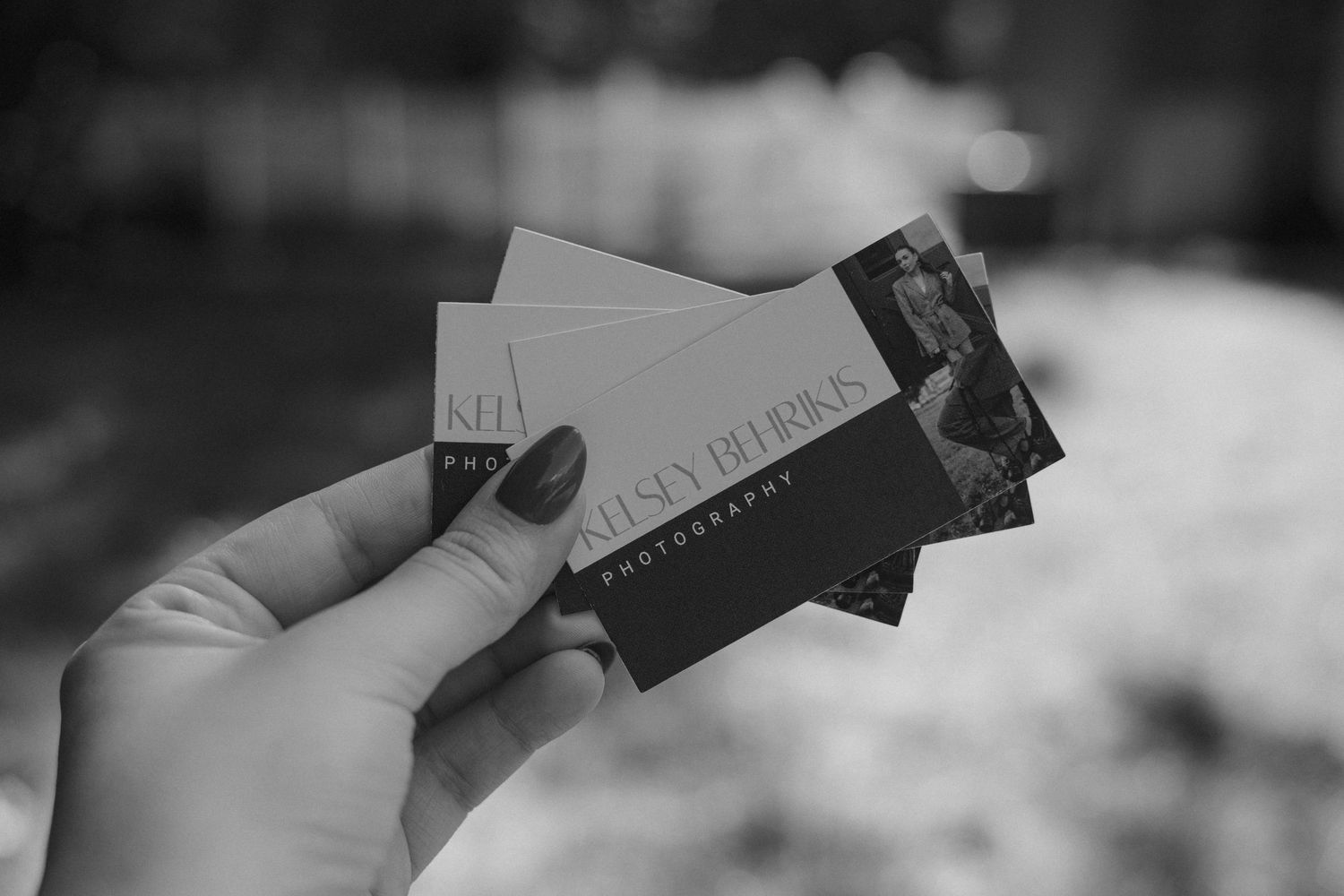 Hand holding Kaitlyn Deeming Photography business cards in black and white photo.