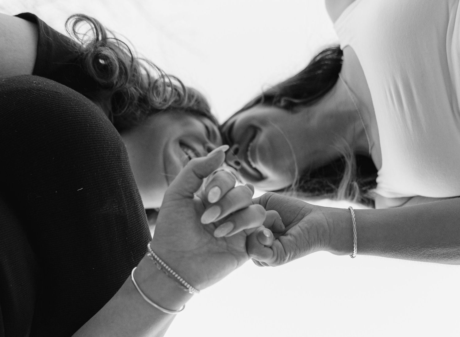 Black and white photo of two young women holding hands and smiling.