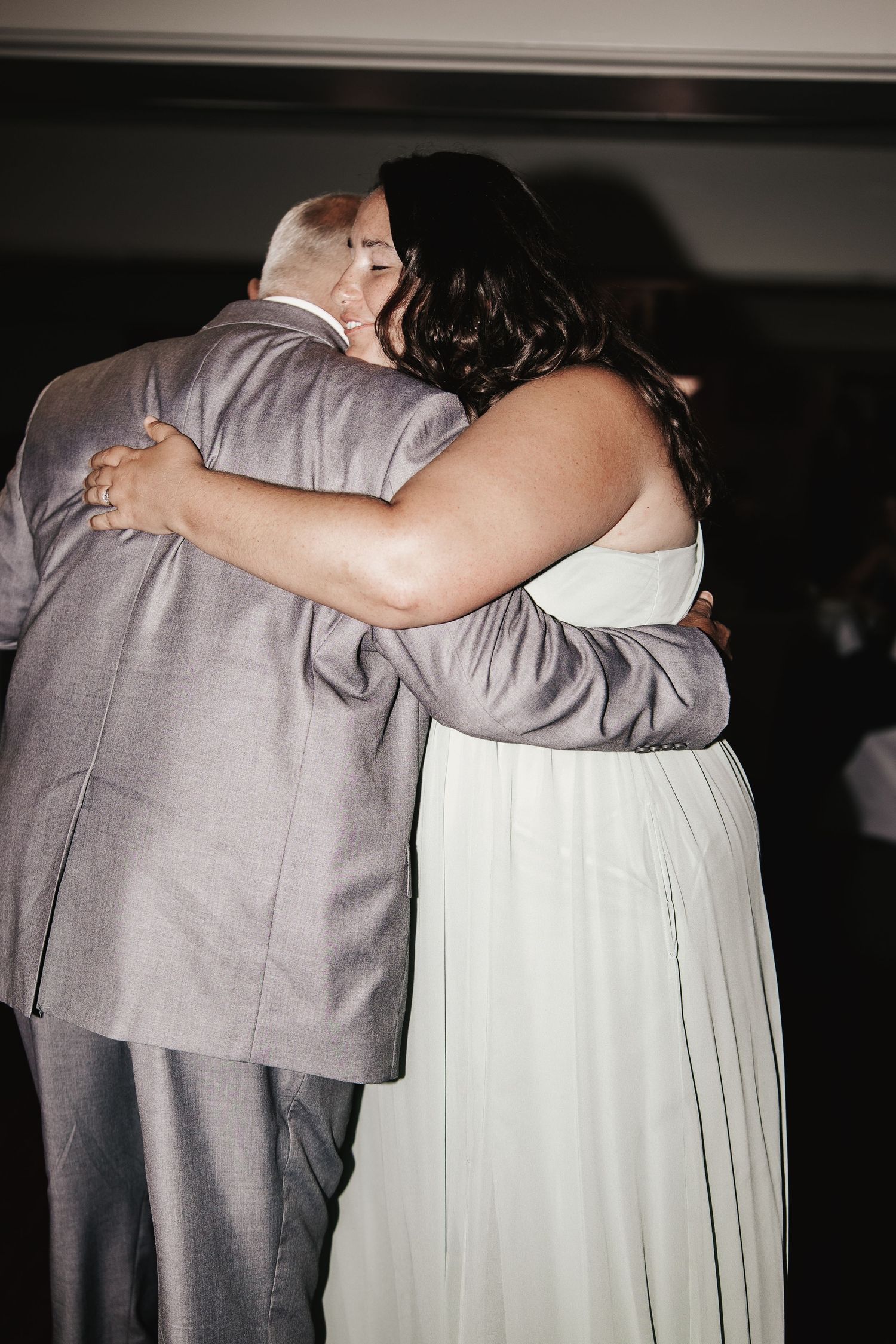 A bride and groom share a tender embrace on the dance floor during their wedding reception.