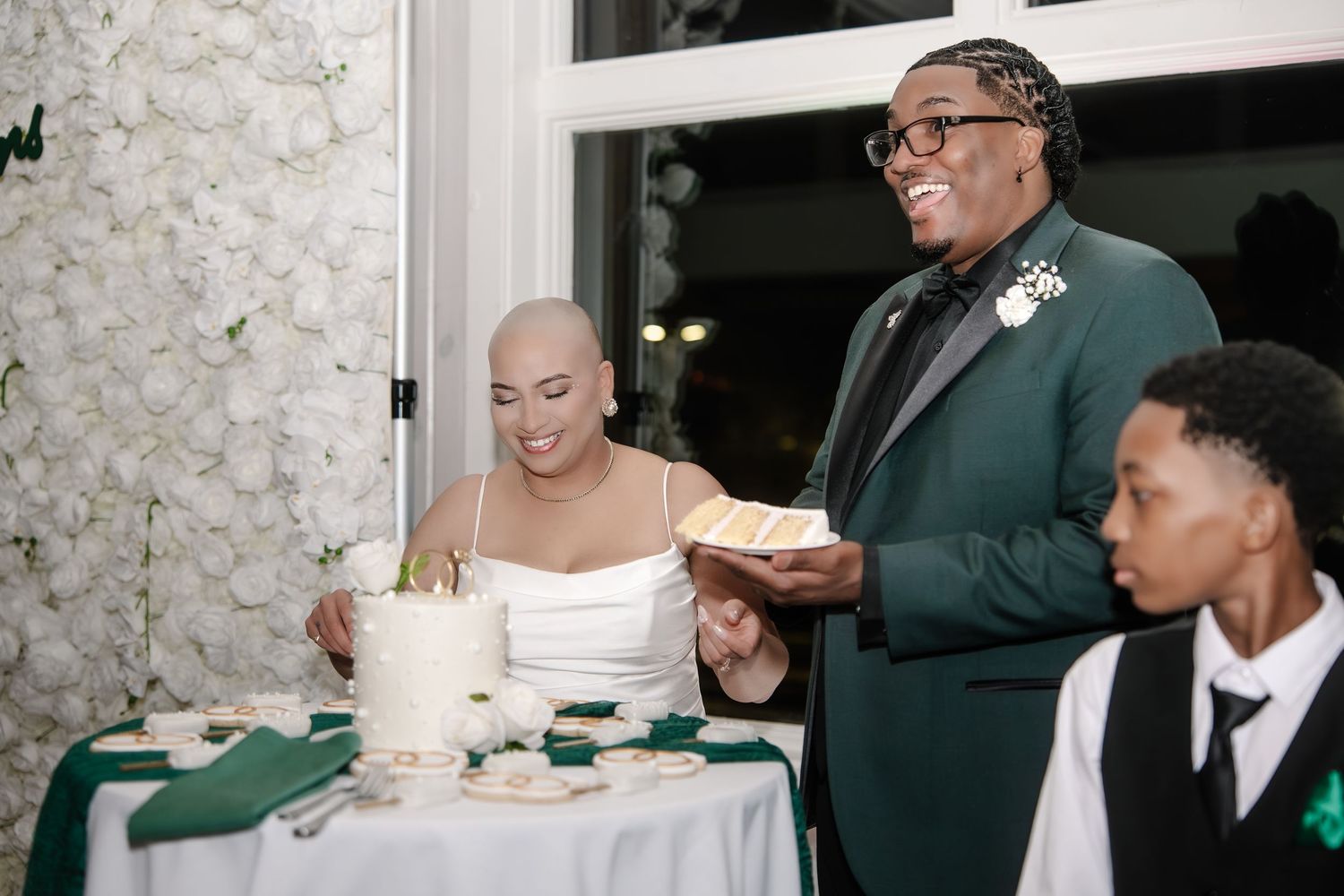Bride and groom cutting wedding cake at elegant green and white themed wedding reception celebration.