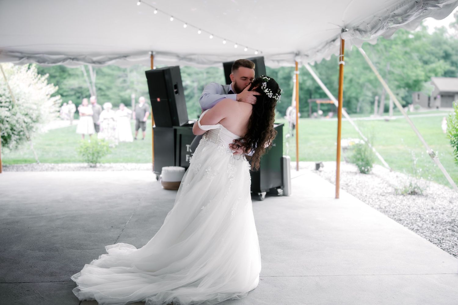 Bride and groom sharing their first dance under a white tent at an outdoor wedding reception.