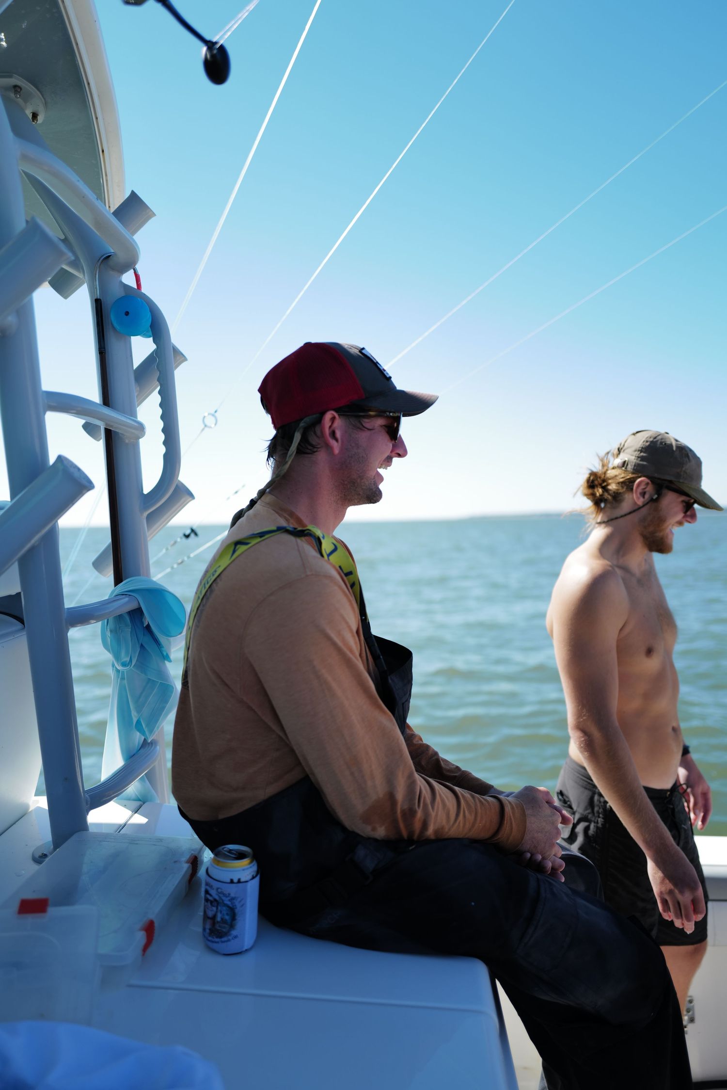 Two young men relaxing on a fishing boat on a sunny day with calm blue ocean water.