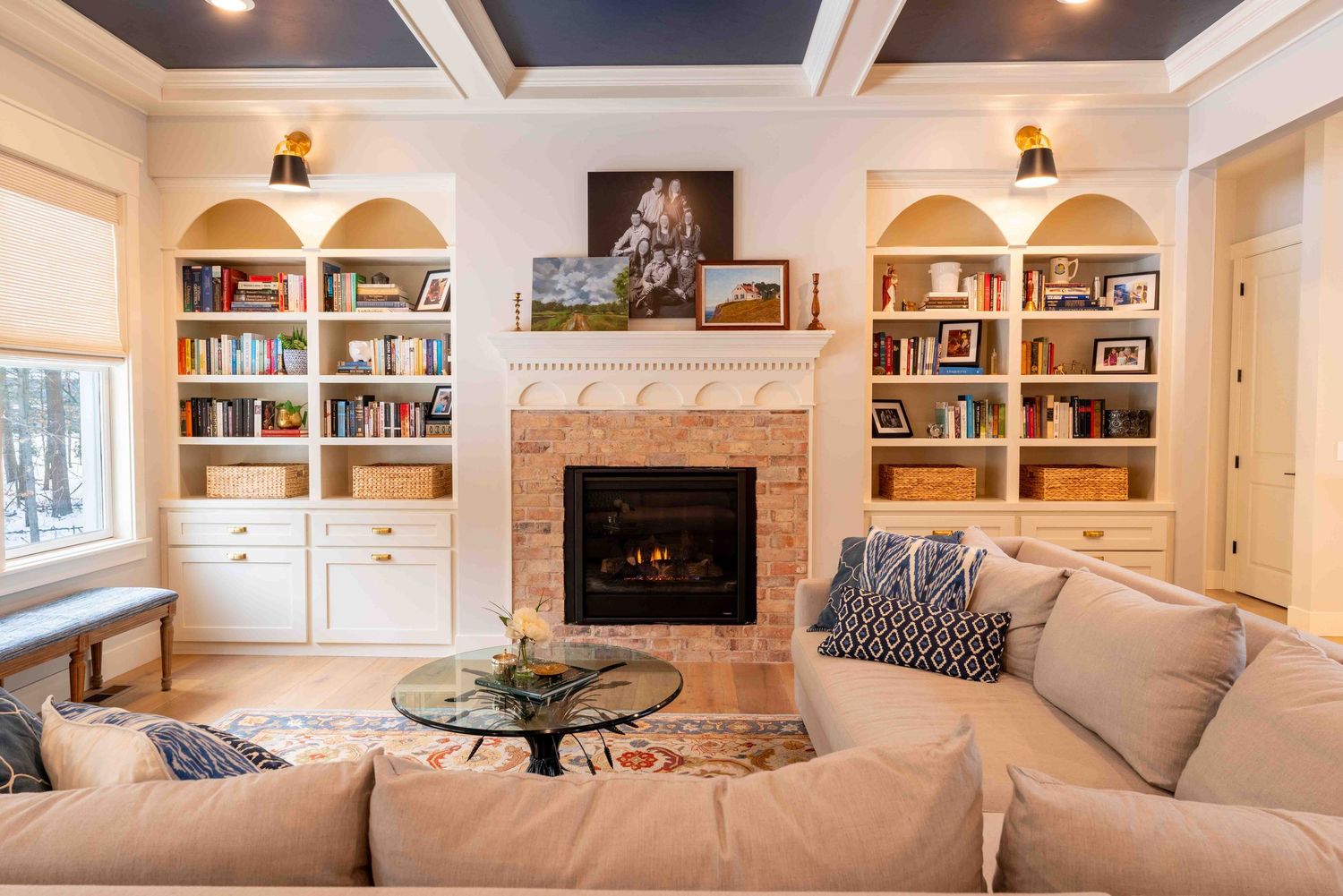 Cozy living room with built-in bookshelves, brick fireplace, and beige sectional sofa.