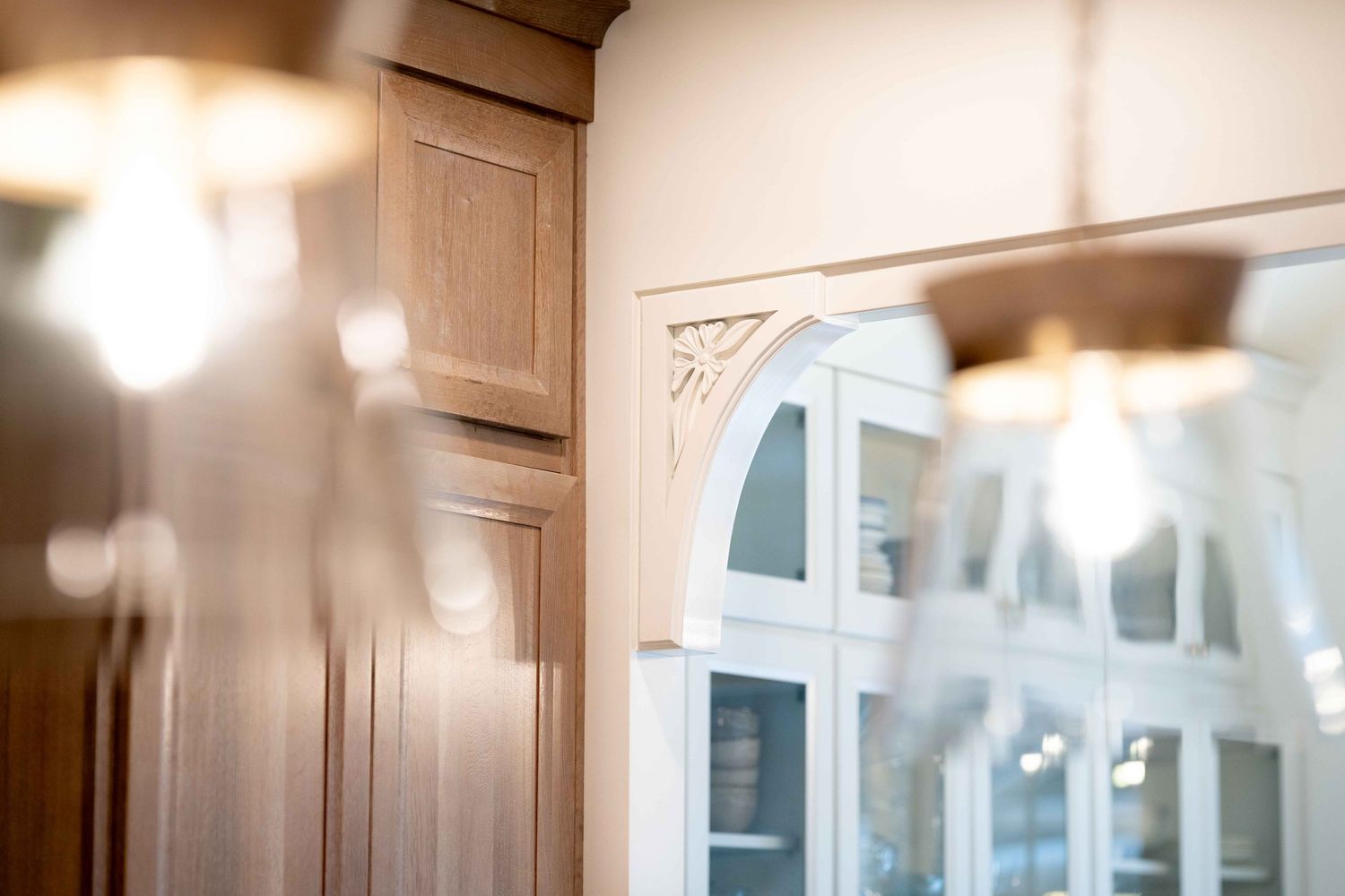 Close-up of decorative white corbel bracket with carved floral detail near glass-front cabinetry.