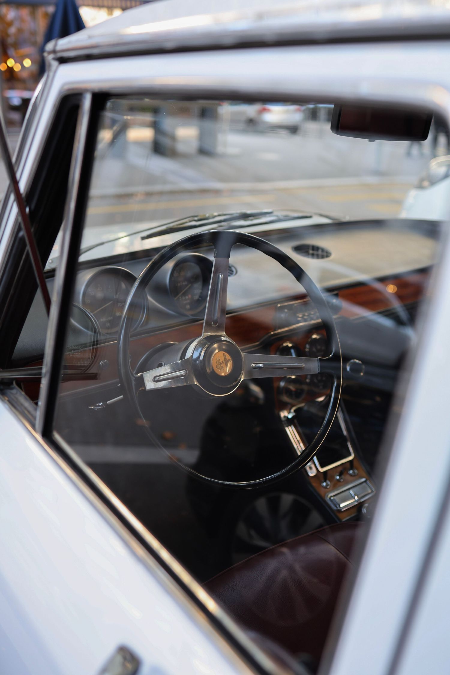 Interior view of a classic vintage car showing a black steering wheel and brown leather seats.
