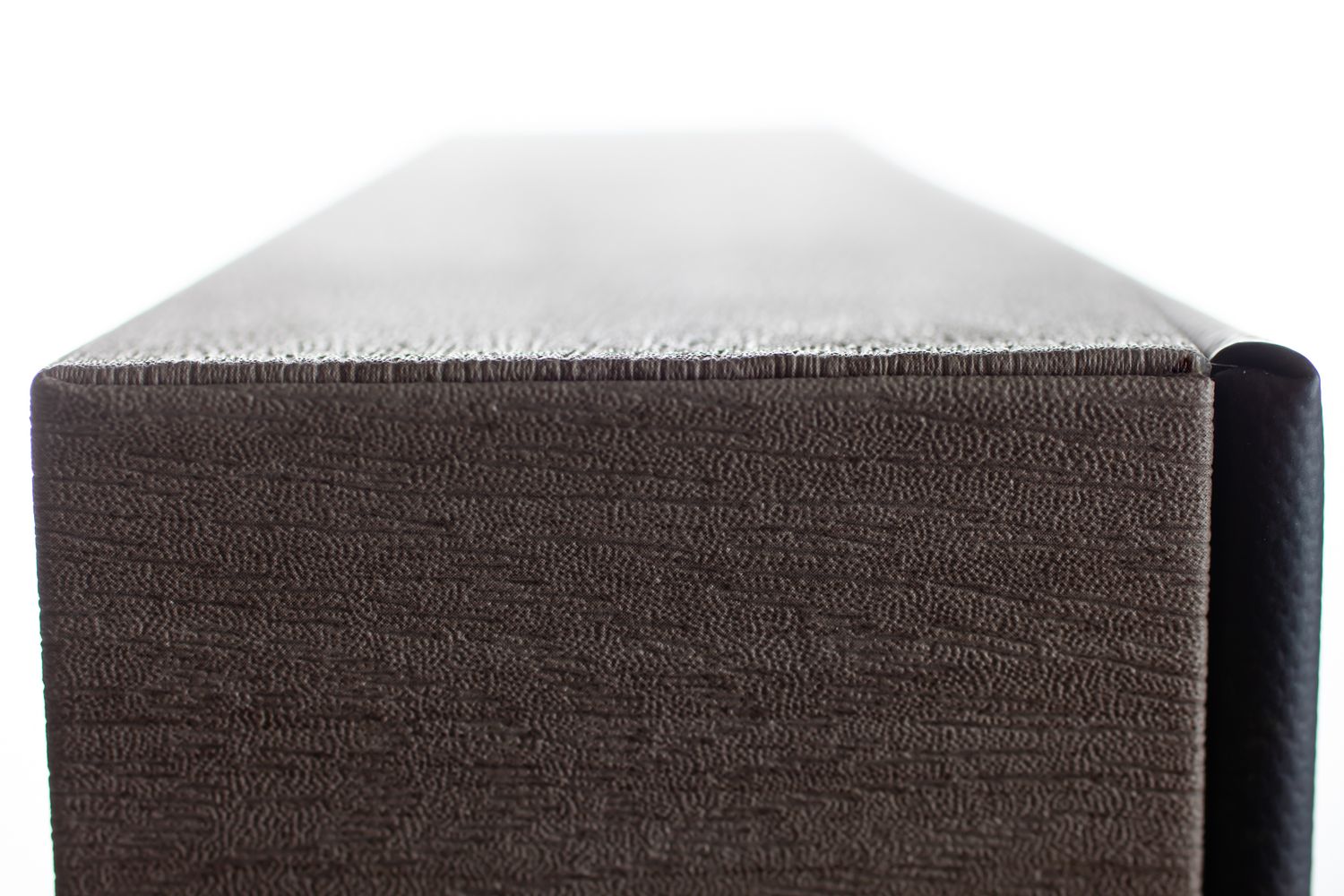 Close-up of a dark brown textured fabric upholstered furniture piece with a smooth gray top surface.