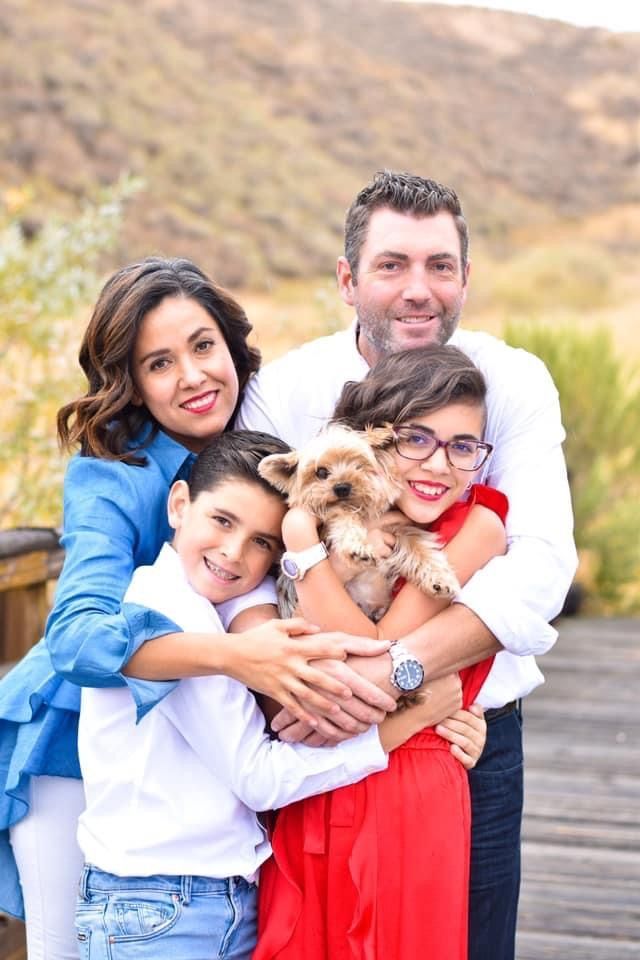 A happy group embraces and smiles together outdoors during a casual photo session on a wooden deck.