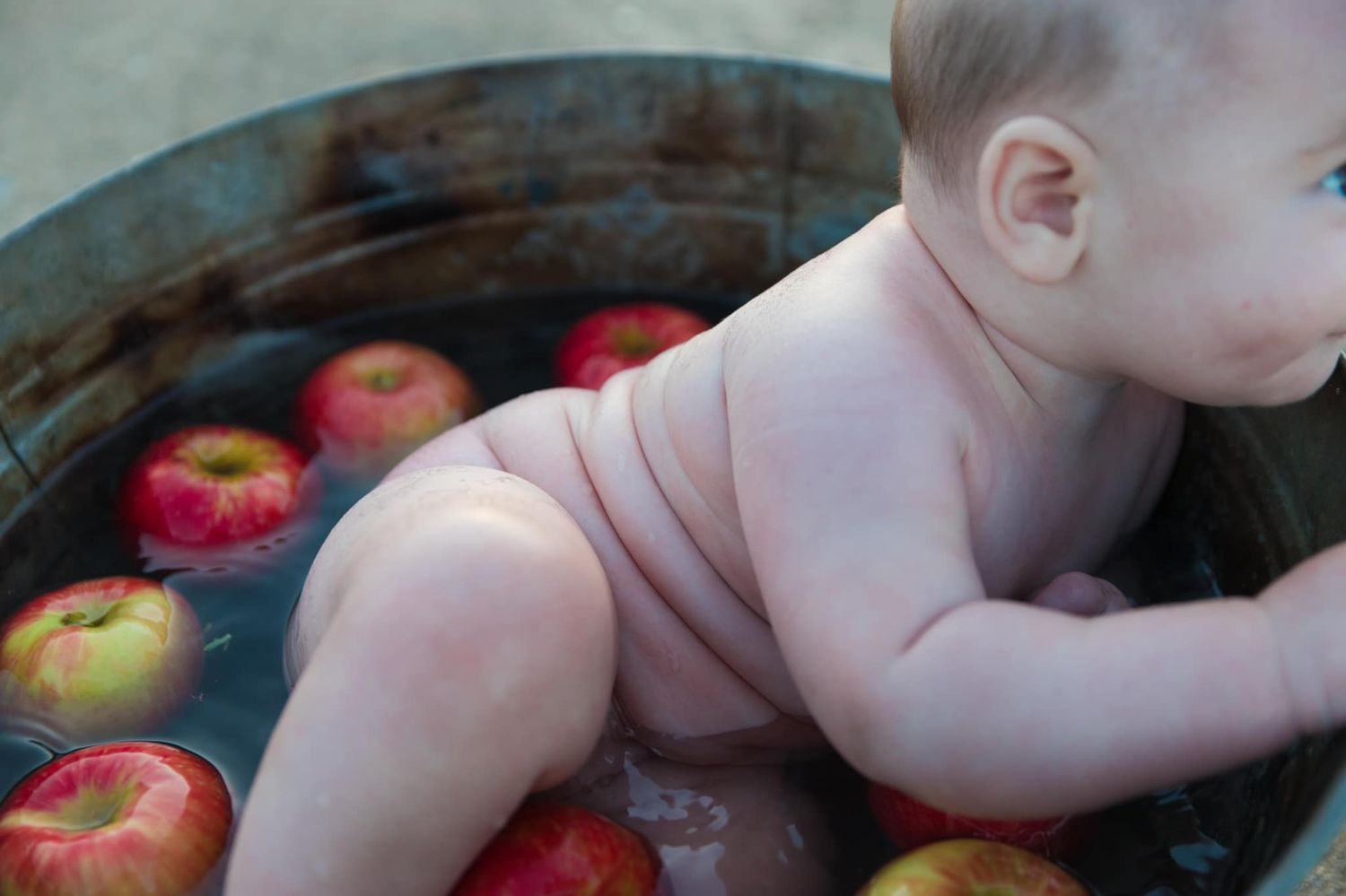 Baby reaching for fresh red apples while sitting in shopping cart at grocery store.