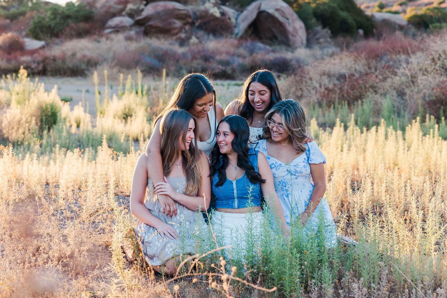 A group in coordinated light blue outfits sharing a joyful moment together in a golden field during sunset.