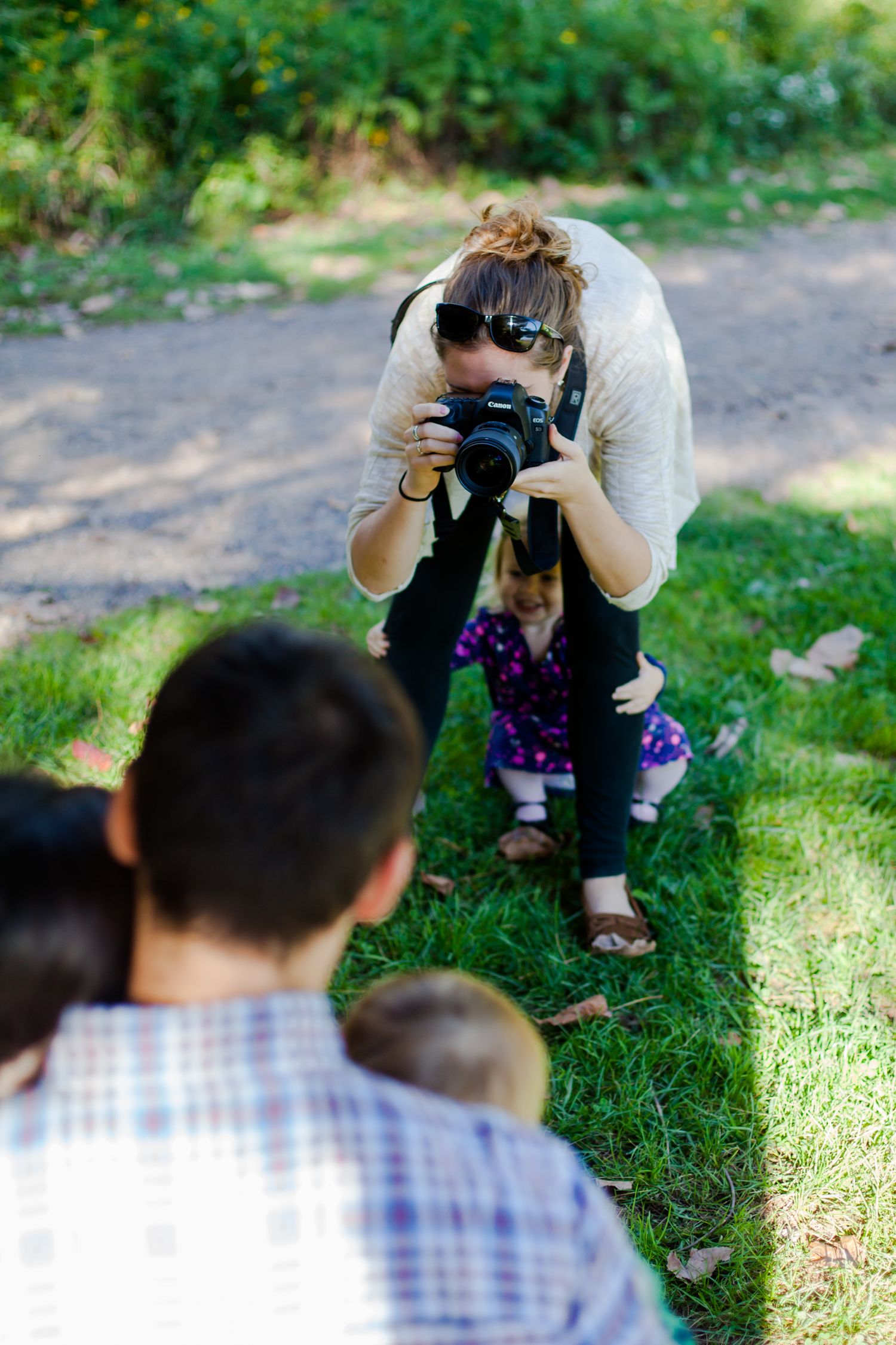 Photographer crouching with camera to take pictures outdoors.