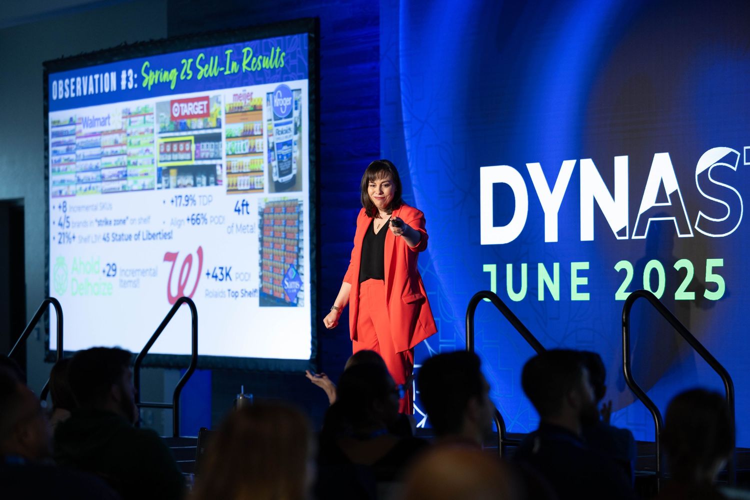Professional conference stage with blue lighting and digital screens displaying presentations in corporate setting.