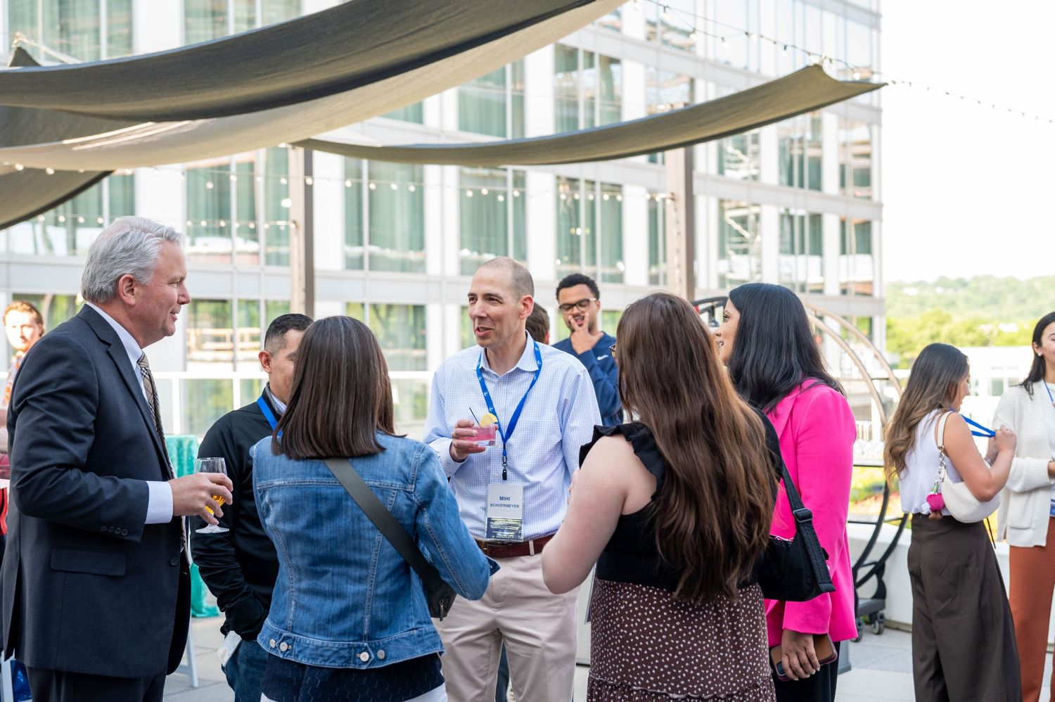 Business professionals networking and socializing at an outdoor covered terrace during a professional event.