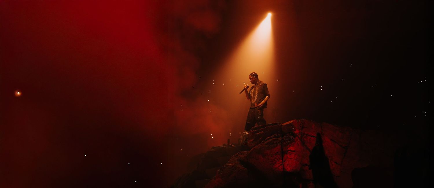 Dark concert venue with red stage lighting and smoke effects creating a dramatic atmospheric ambiance.