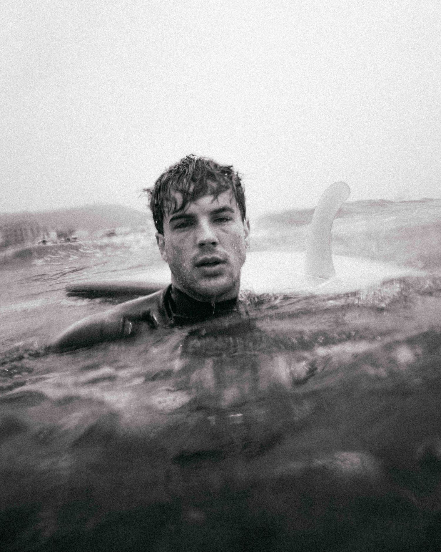 Black and white photo of someone swimming in choppy ocean waters.