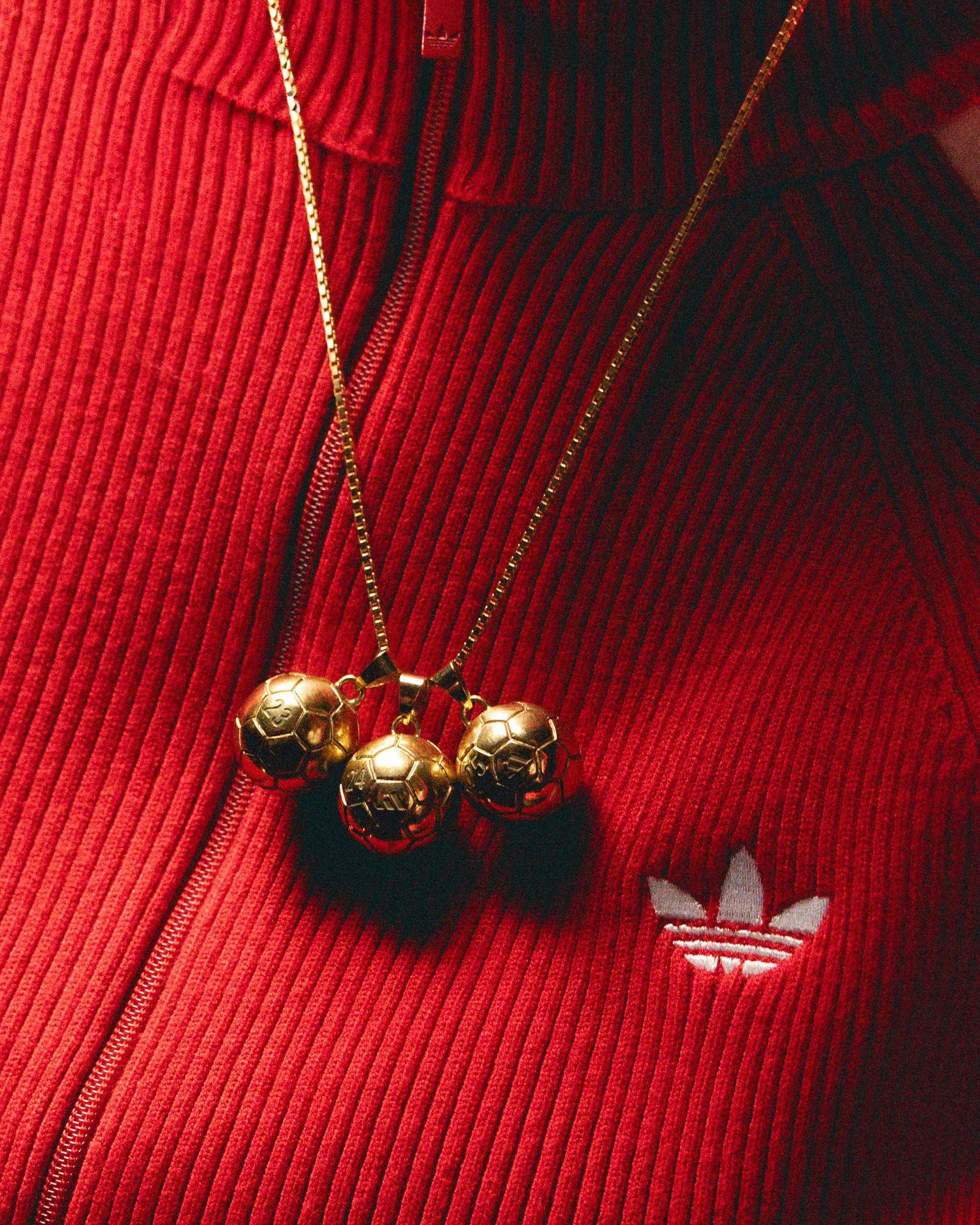 Gold necklace with black beads displayed against a vibrant red corduroy fabric background.