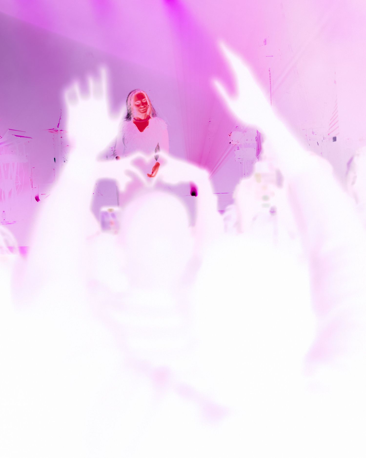 Concert performer surrounded by ethereal pink lighting effects and crowd silhouettes.