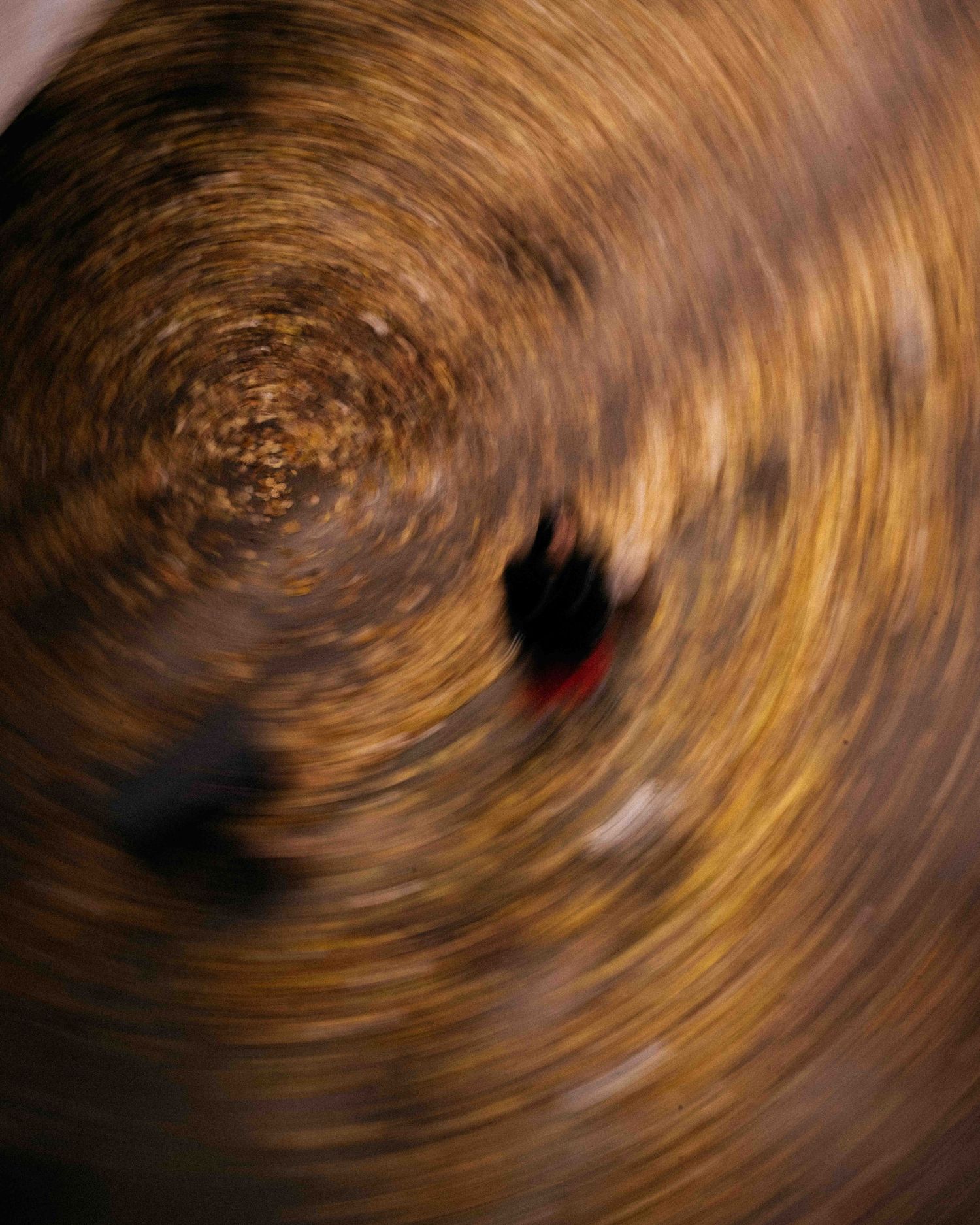 Abstract swirling motion blur in golden brown tones creating a hypnotic spiral pattern with dark center.