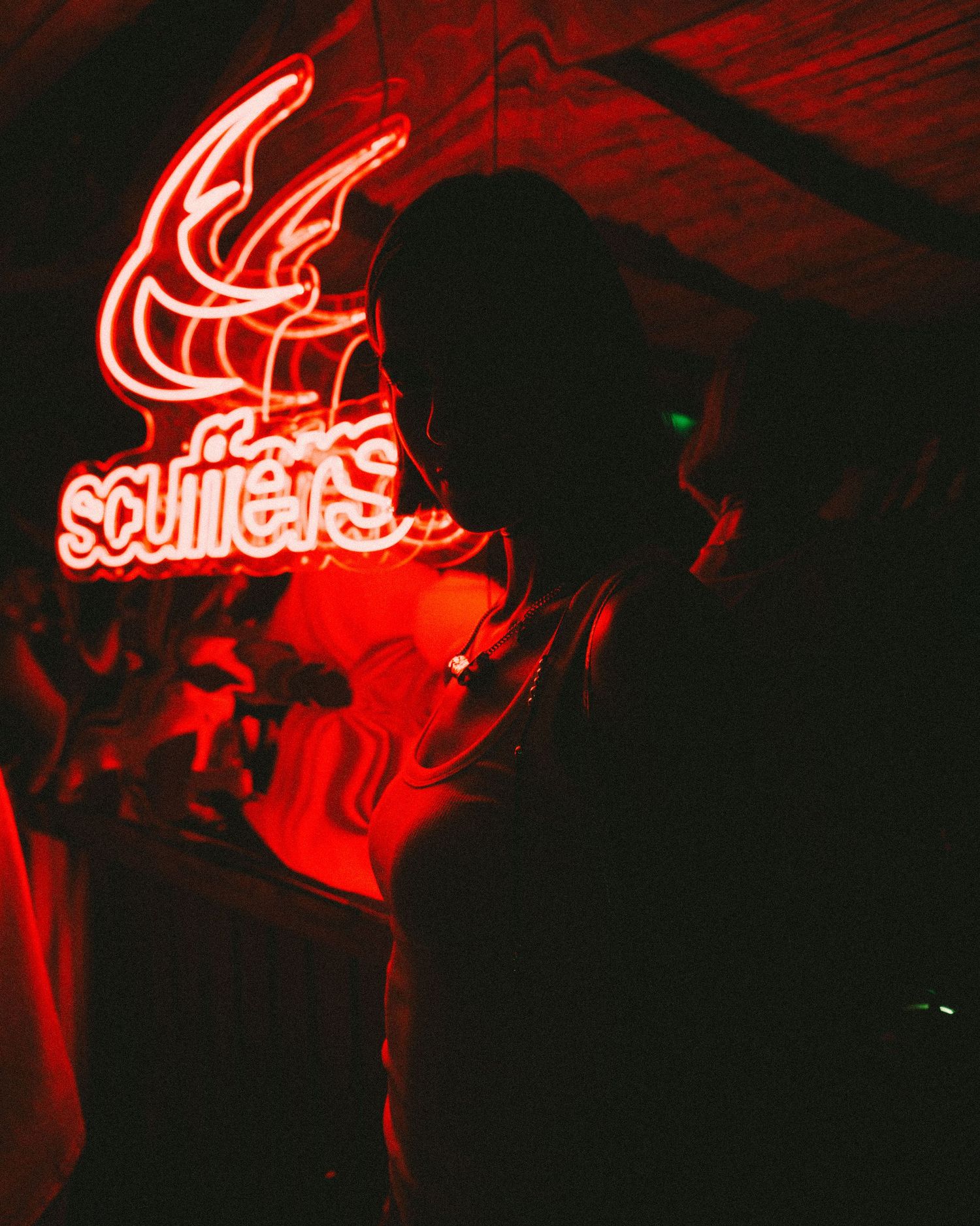 Red neon sign glowing in darkness with 'Scooters' text.