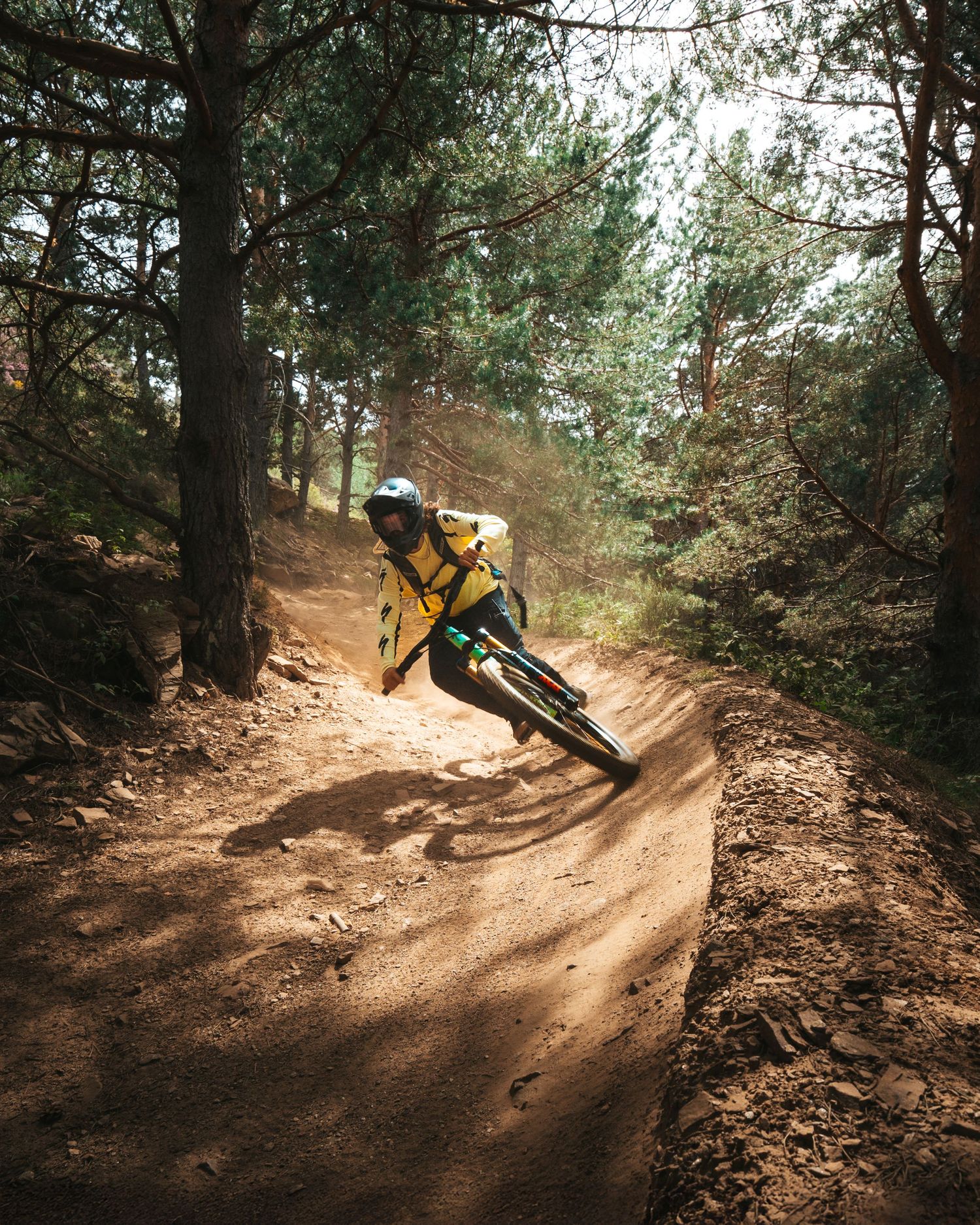 Mountain biker carving through a dusty forest trail with dynamic lighting and shadows.