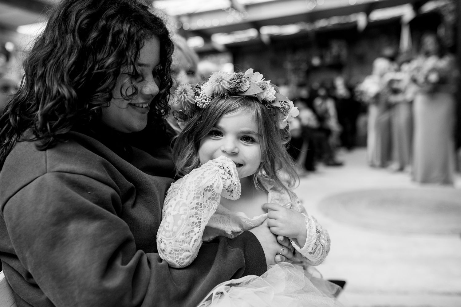 A tender black and white moment between parent and child with a delicate lace dress and floral crown.