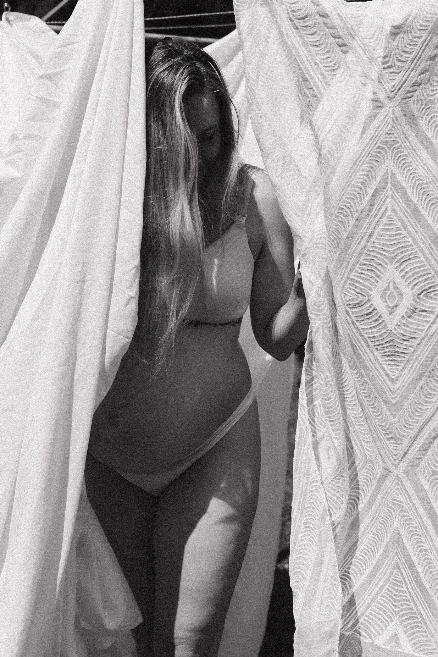 A dramatic black and white series showing a figure behind sheer white patterned curtains in a sunlit room.