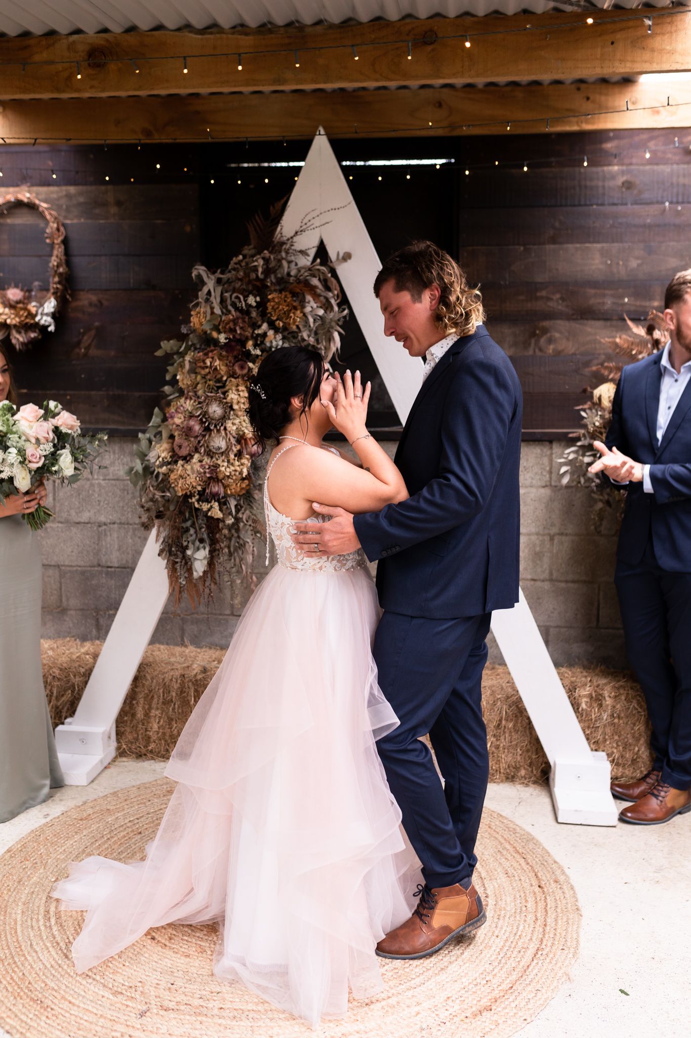 First dance moment in front of a triangular backdrop with dried floral arrangements.