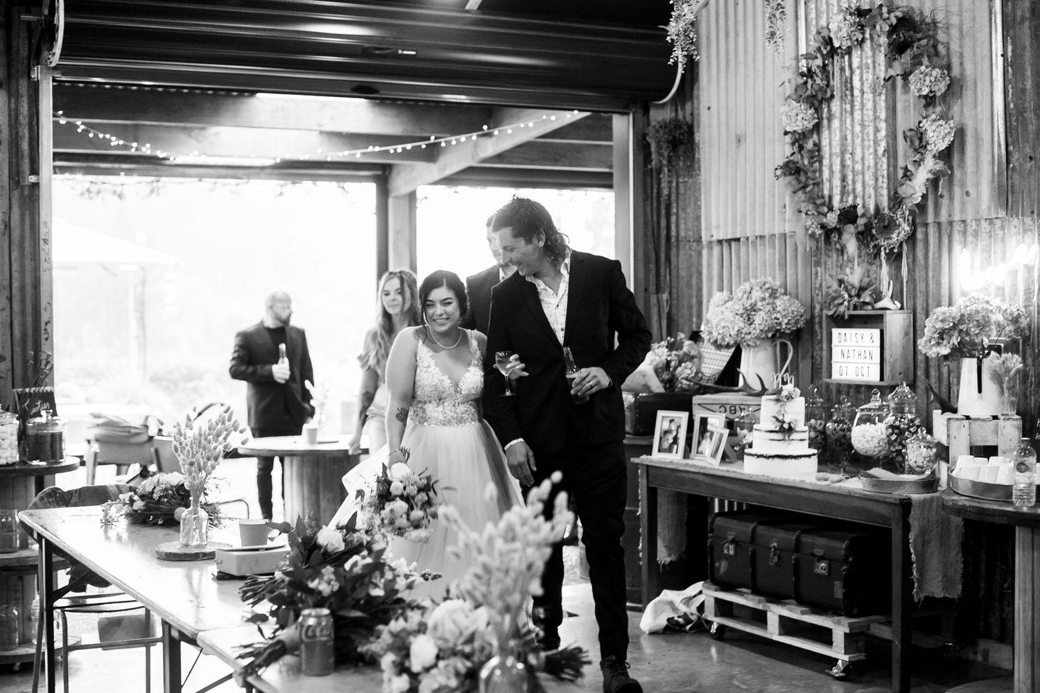 A black and white indoor wedding reception photo showing celebration in a rustic venue.
