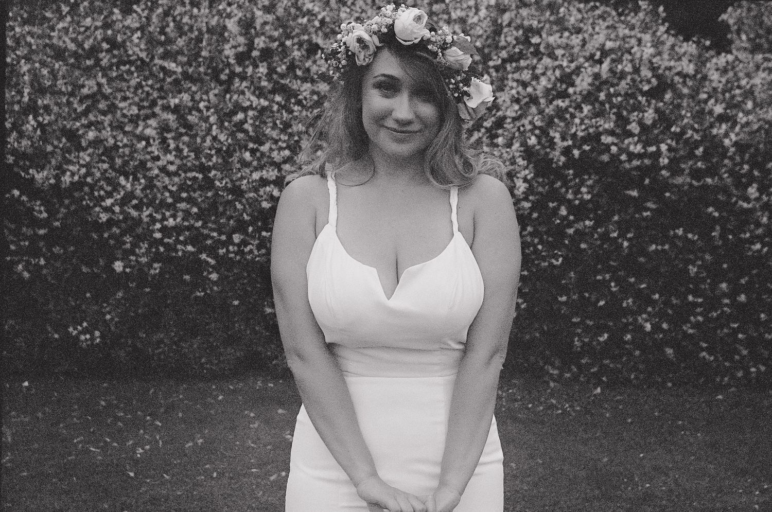 A series of black and white photos showing someone in a white sleeveless dress against a leafy background.