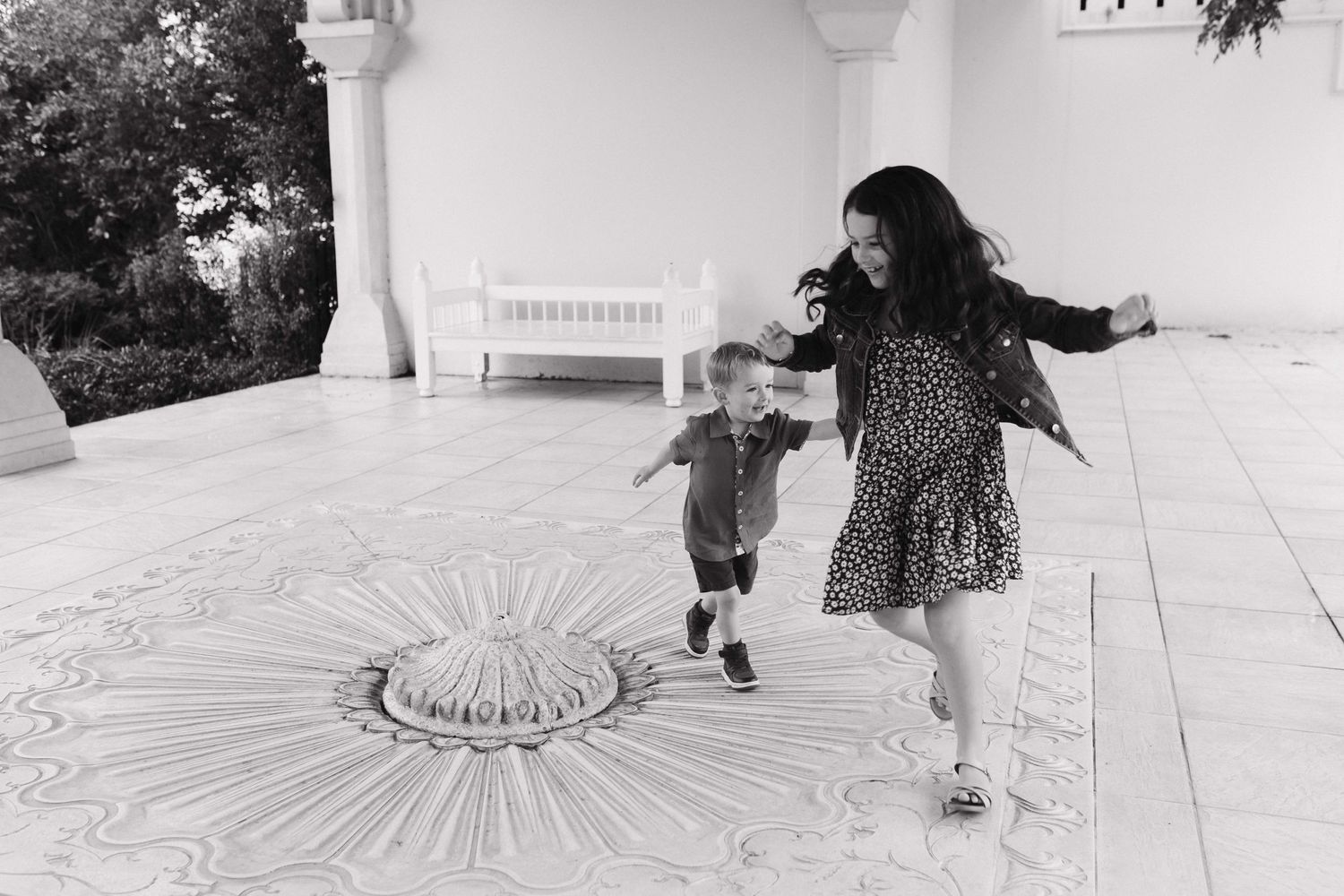 Two people dancing and twirling together on a white tiled patio.