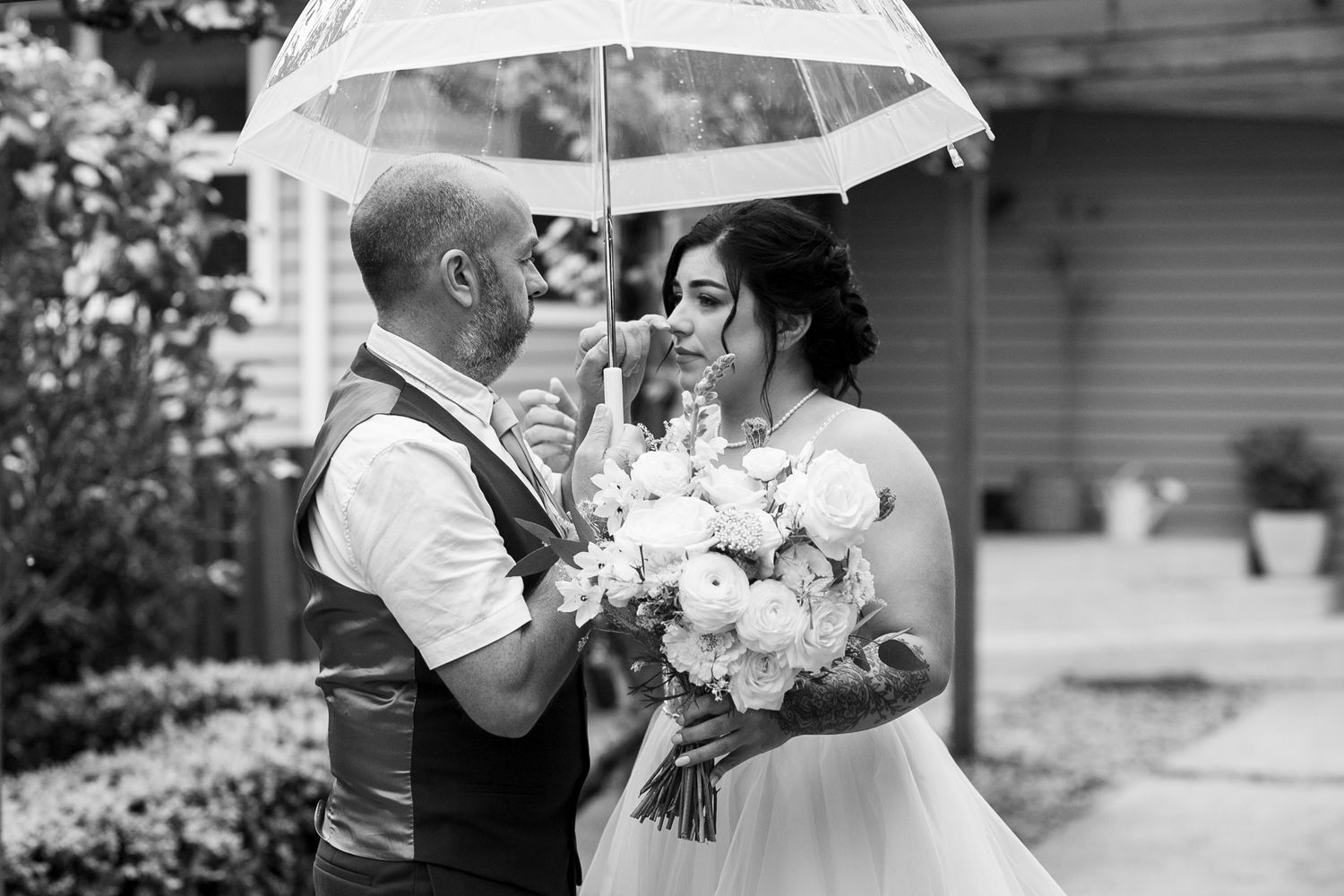 A romantic moment under a clear umbrella during a wedding photoshoot.